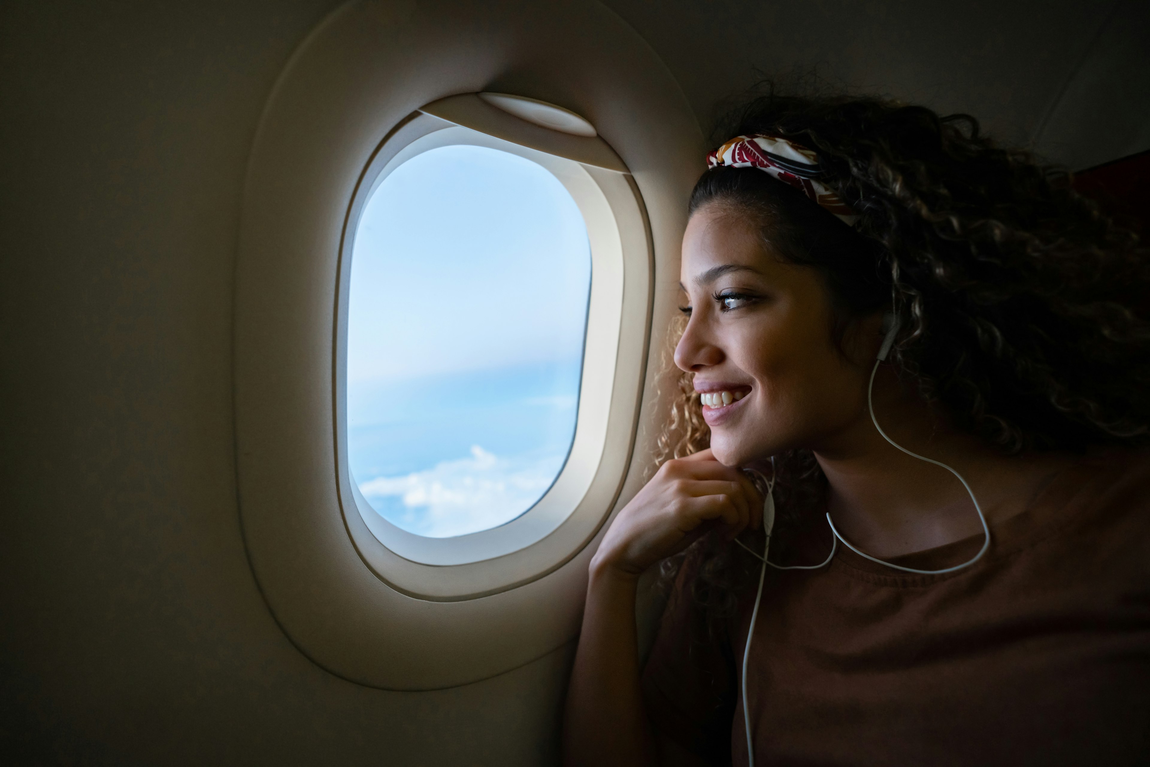 Male passenger sits in an airplane next to the window with a mobile phone.