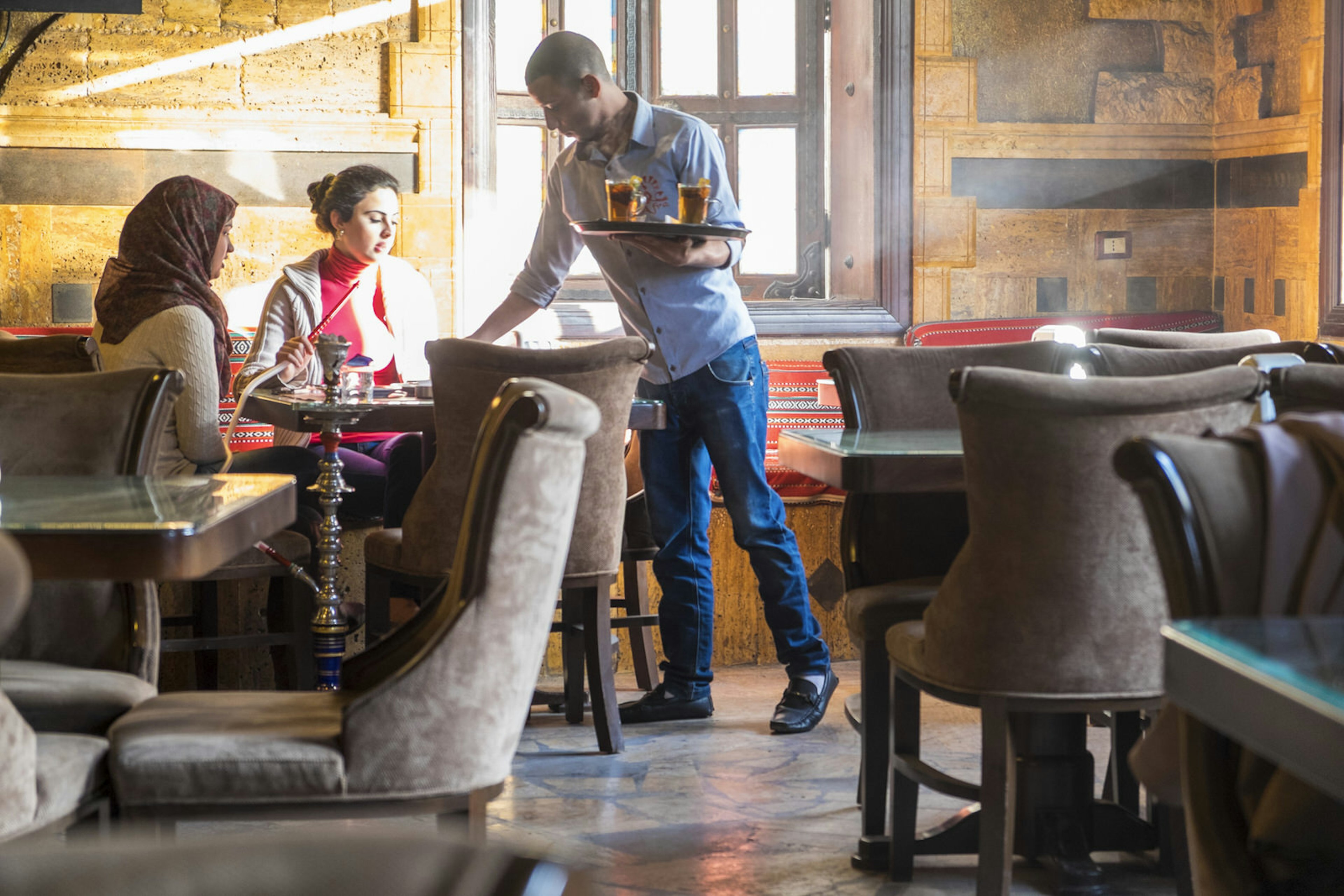 Women smoking shisha and being served tea in a cafe in downtown Amman, Jordan © Peter Adams / Getty Images