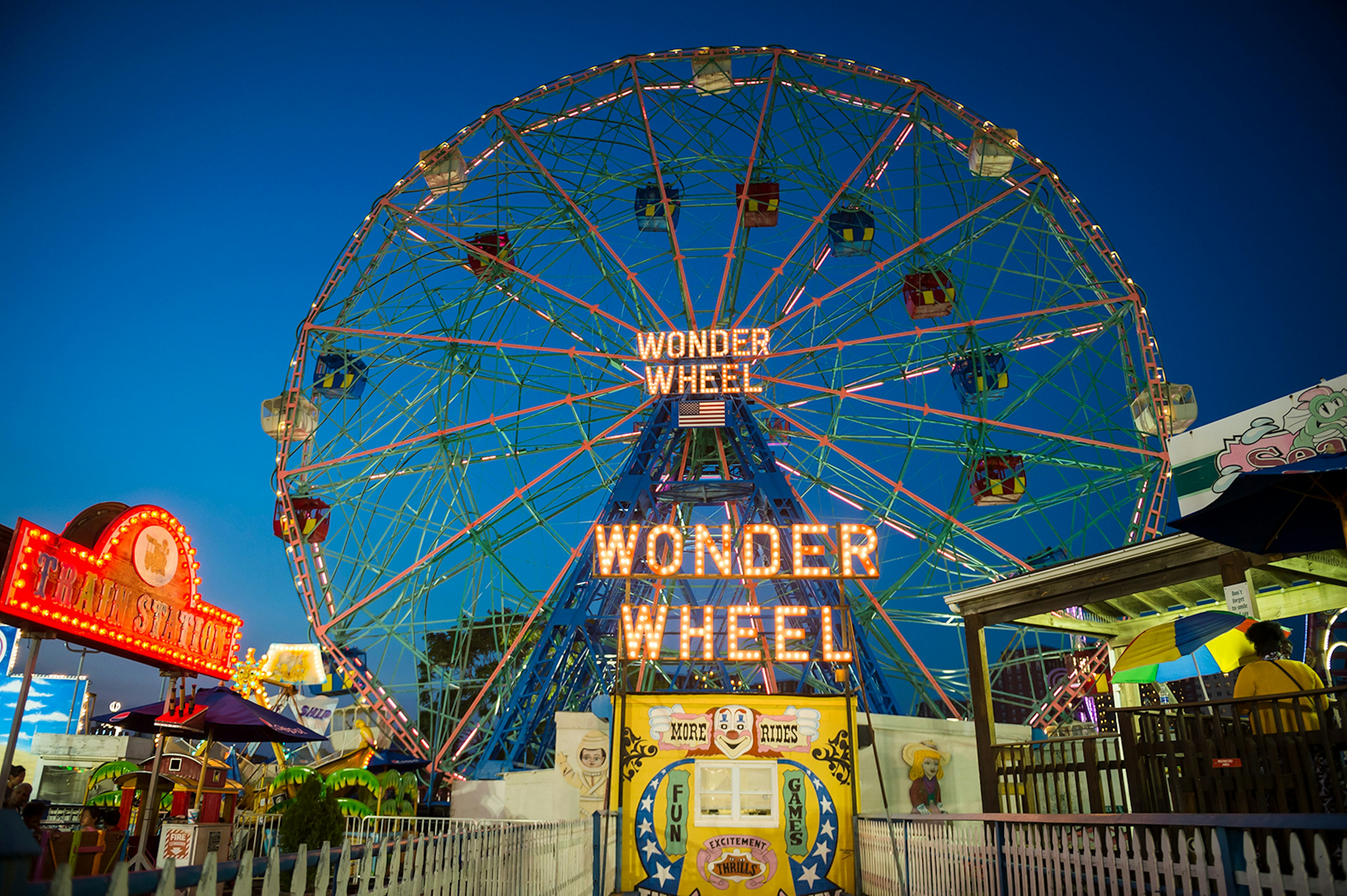 The wonder wheel Ferris Wheel is lit up over Coney Island amusement park in New York at night; ways to enjoy New York City in the summer