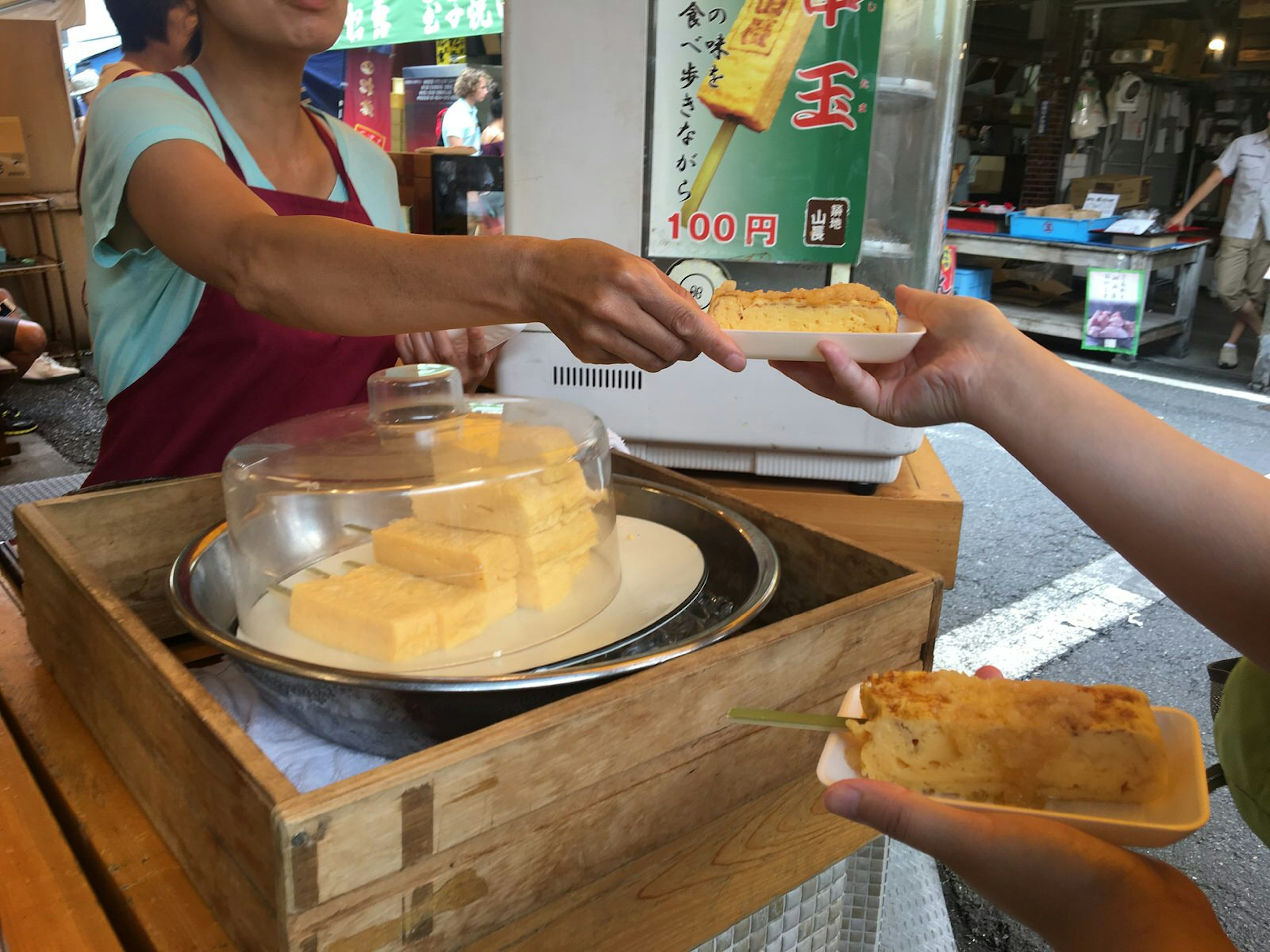 Staff member at Yamachō hands a plat of rolled omelette (tamago-yaki) to a customer © Rebecca Milner / Lonely Planet