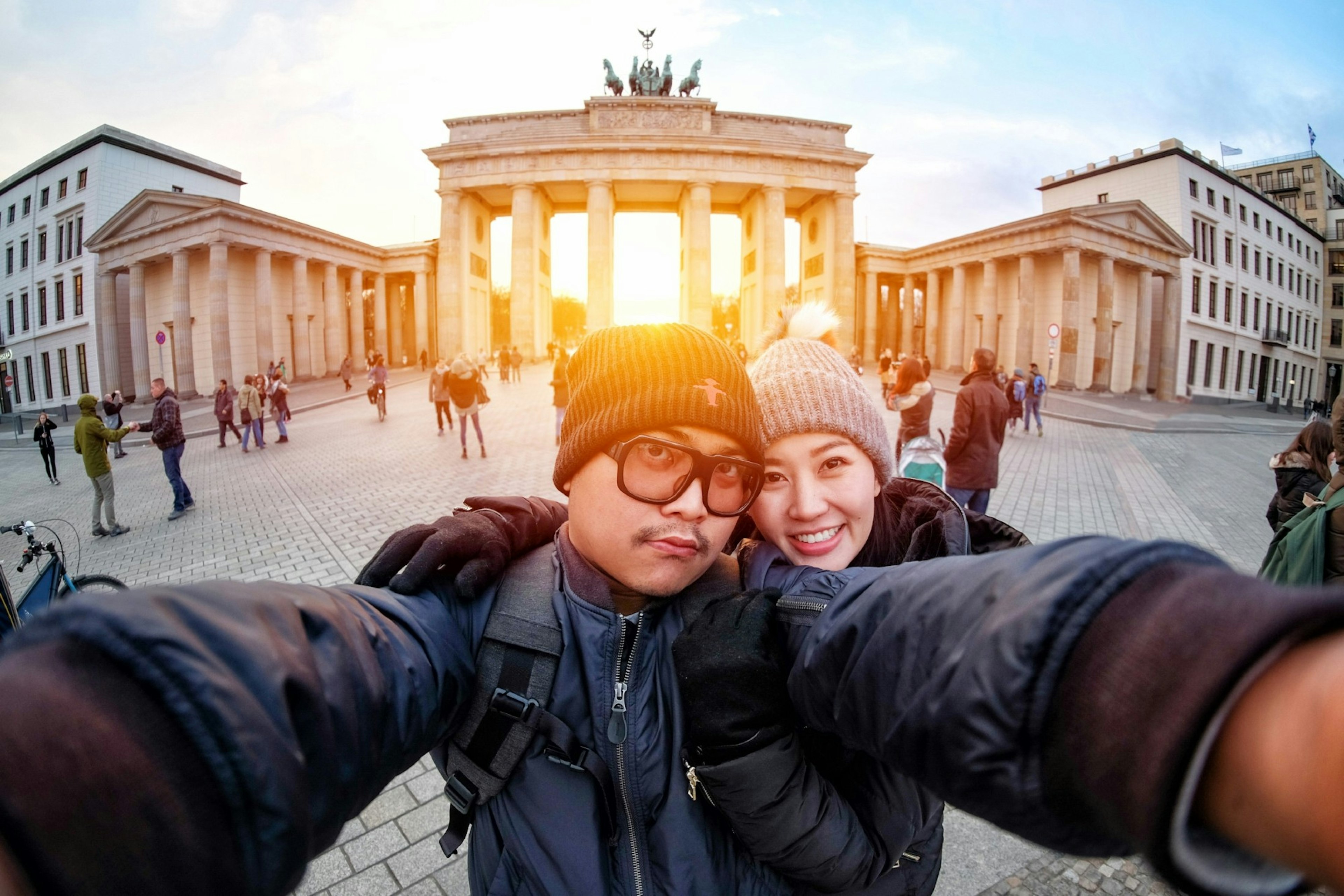 Young couple take a selfie with a smartphone at the Brandenburg Gate in sunlight, the famous landmark of Berlin