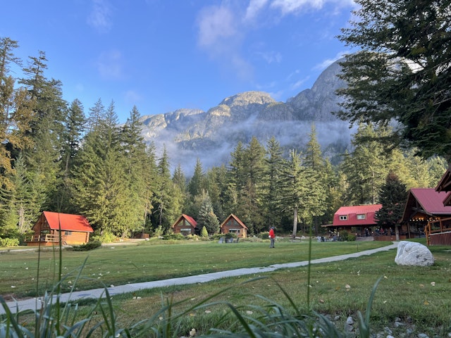 a group of cabins with rocky mountains behind Tweedsmuir