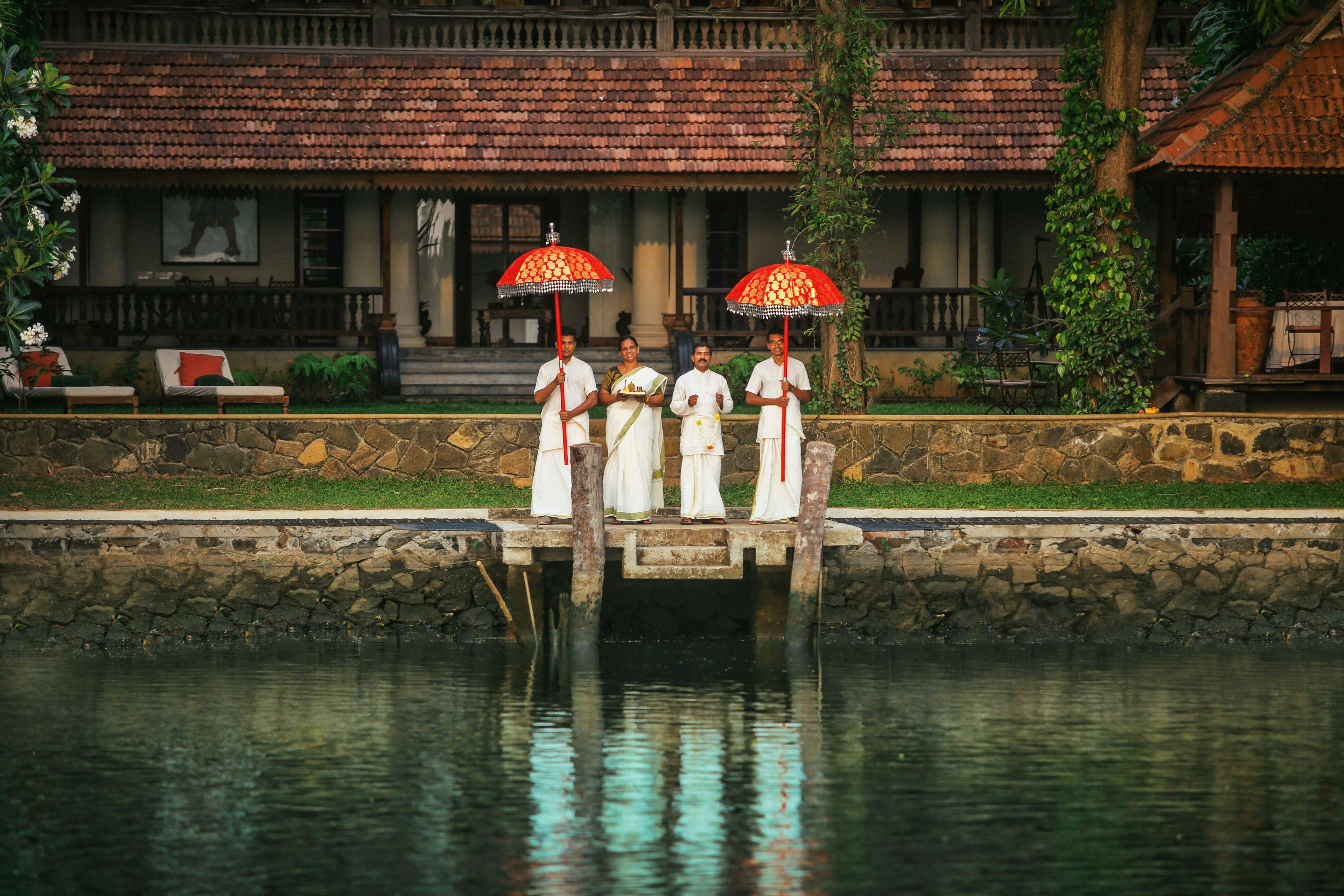 Four members of staff wait on a small hotel jetty to welcome guests approaching by boat