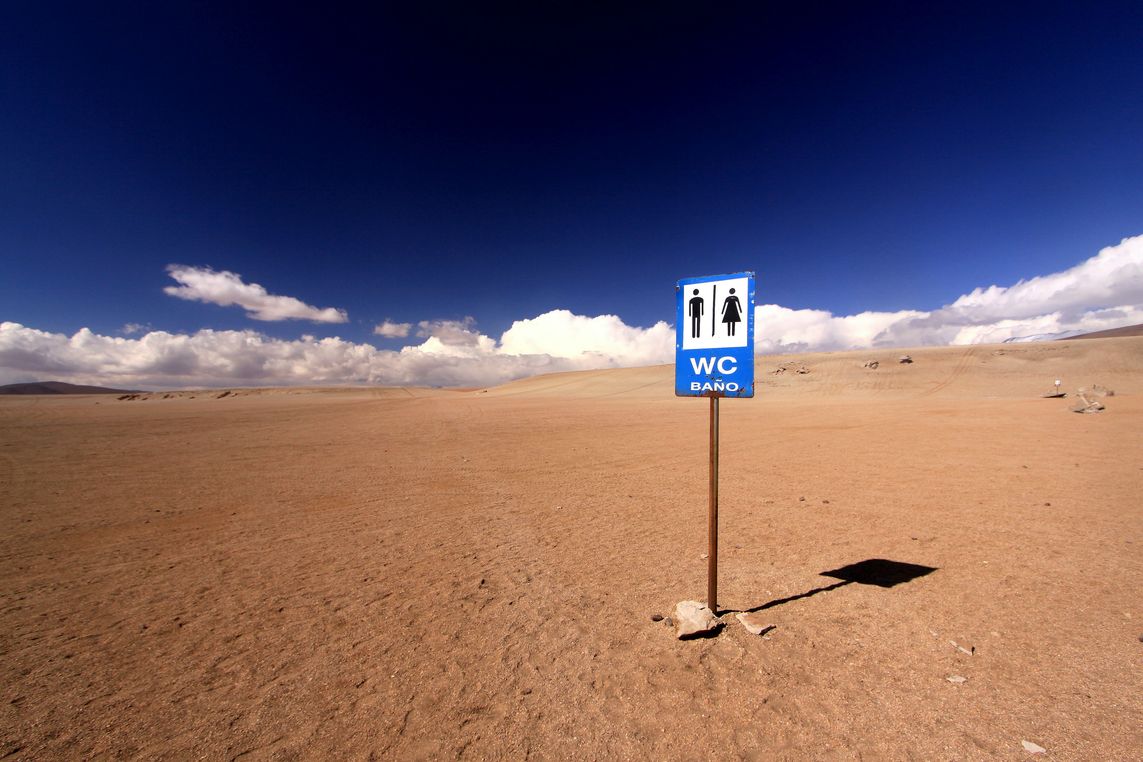 A sign for the toilet in the Siloli Desert, with clouds hanging