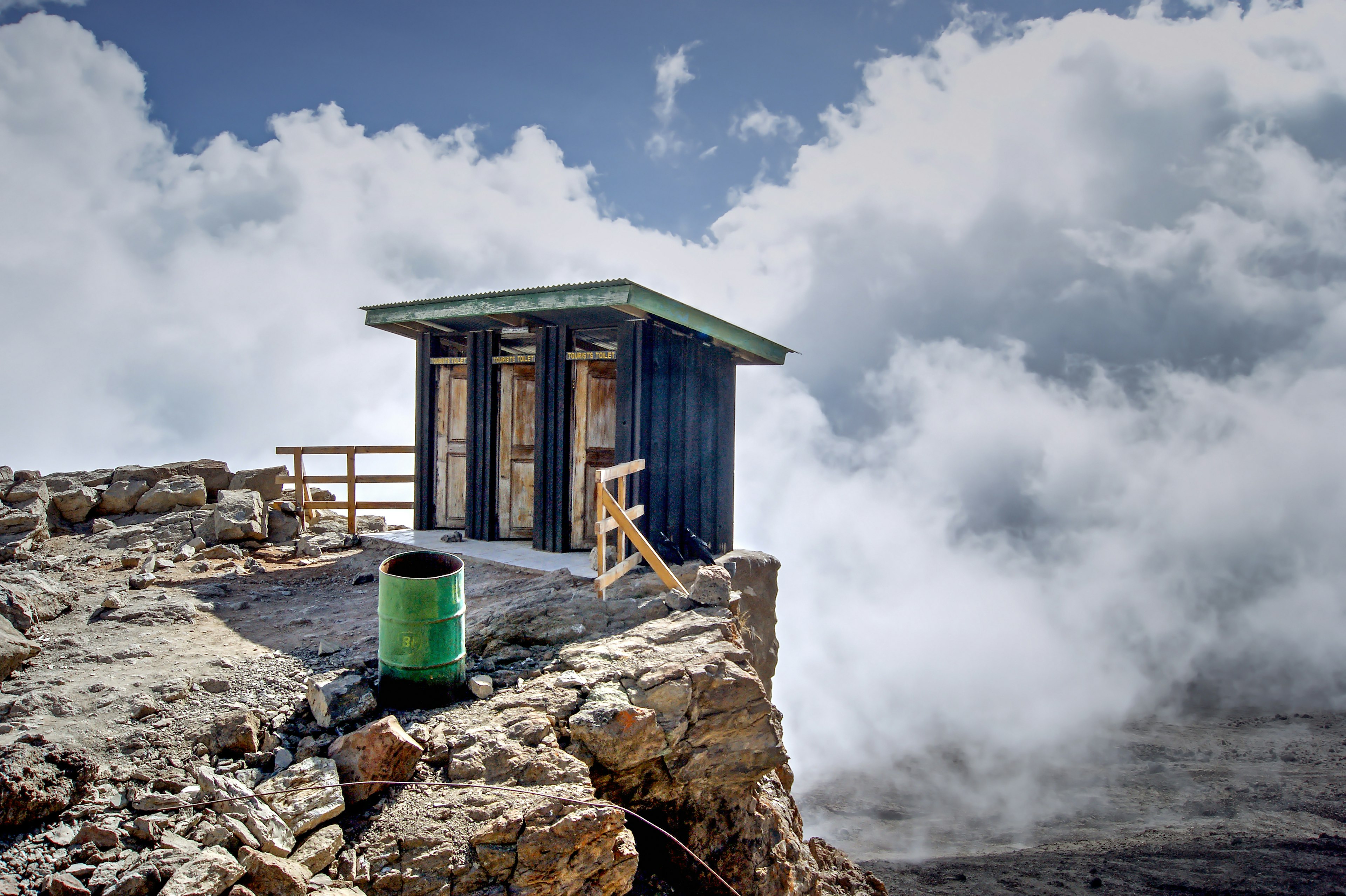 A toilet precipitously perched on the edge of a cliff.