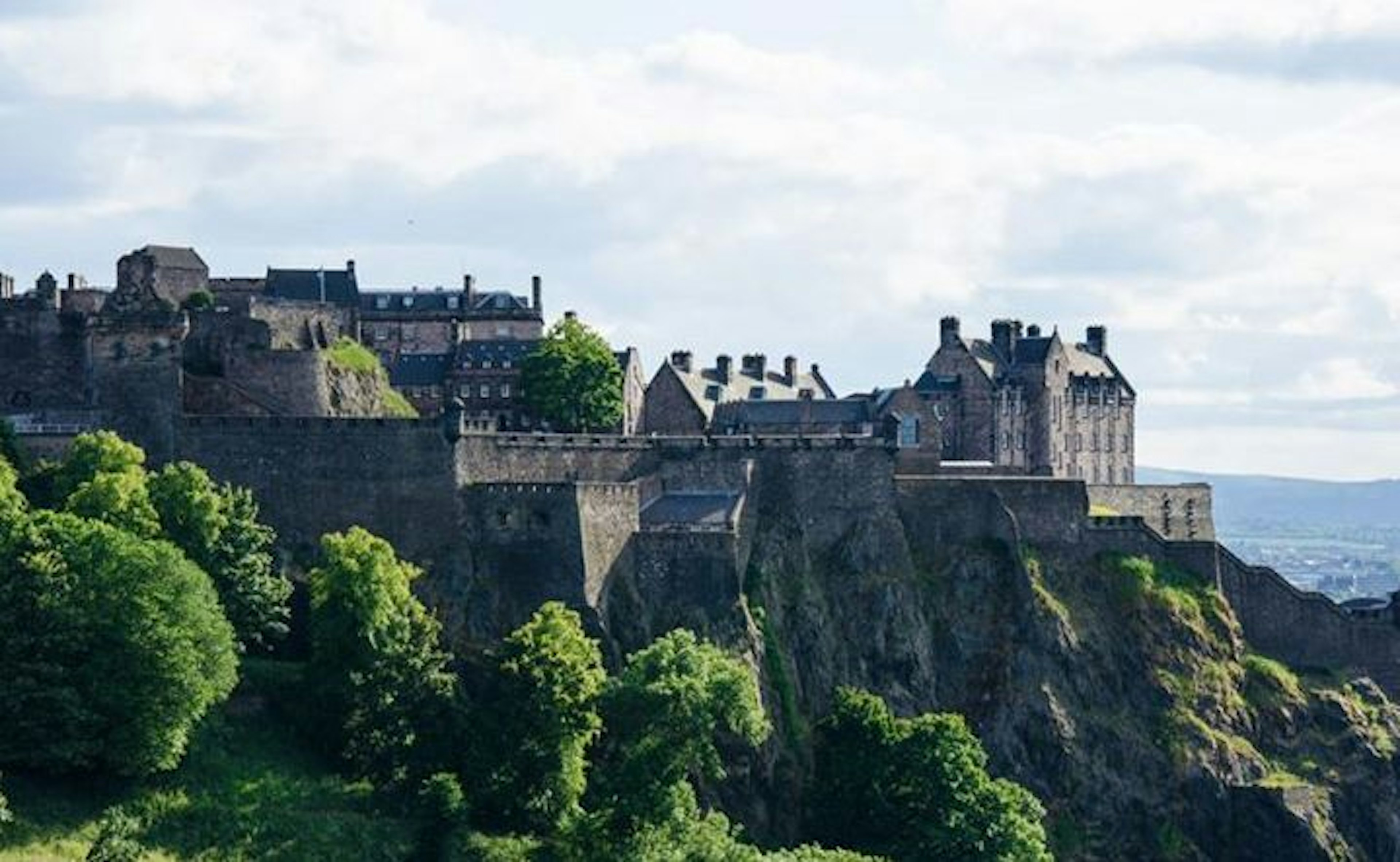 Edinburgh Castle, seen from a distance with cloudy skies overhead.