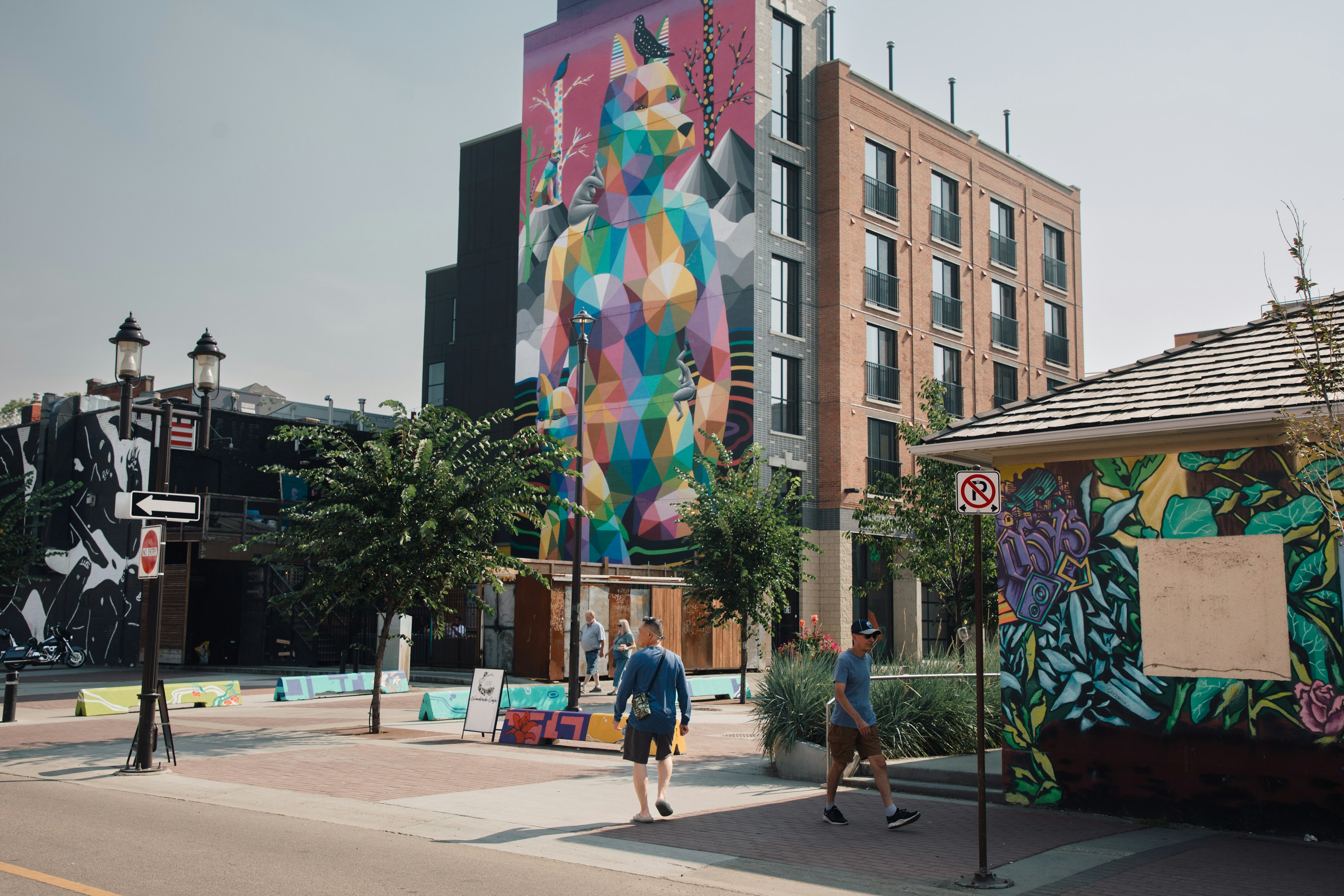 A man walks in front of a huge, colorful mural on the side of a building on Whyte Ave in Edmonton, Alberta, Canada