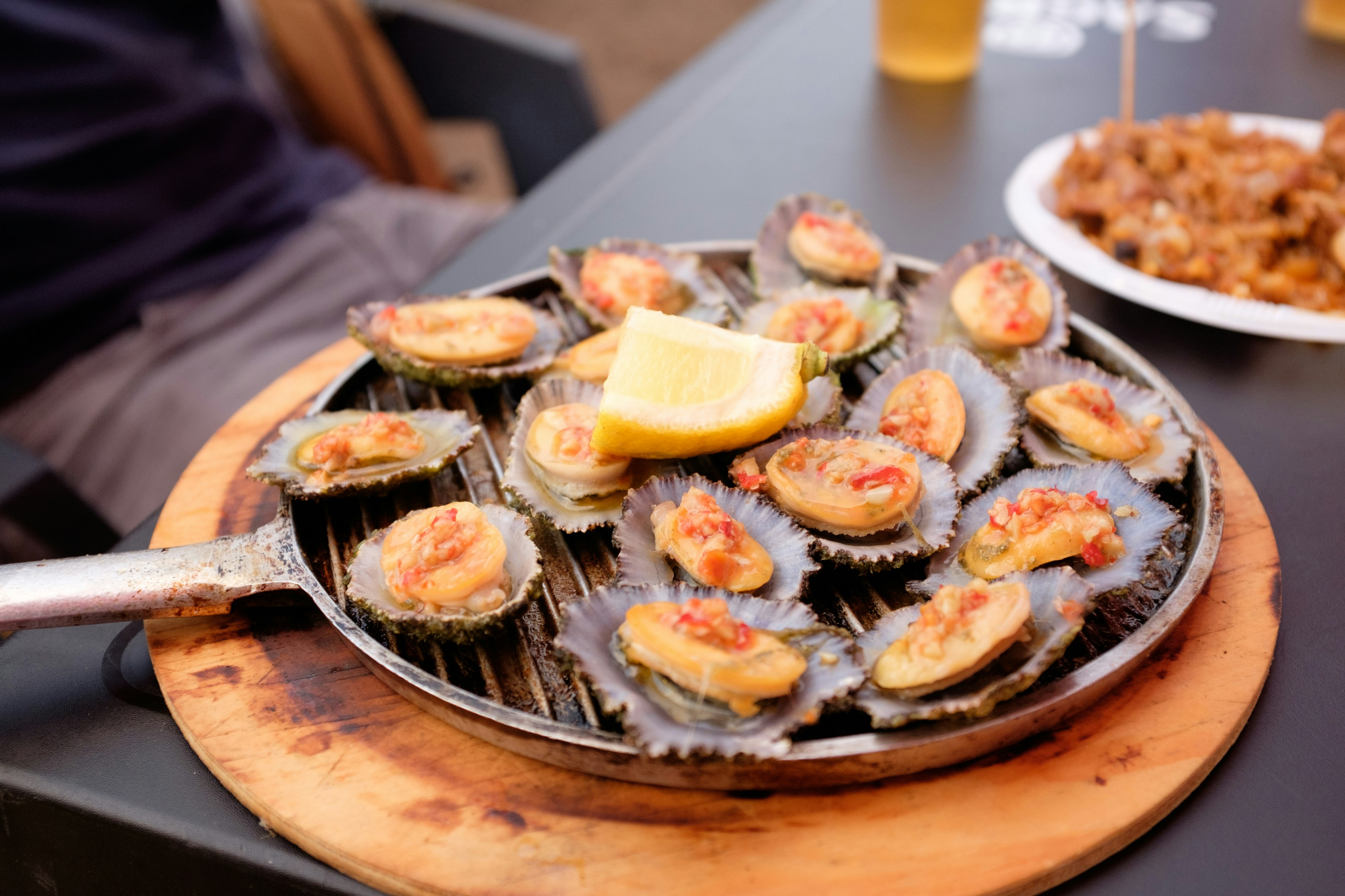 A griddle laden with fish in shells served with a chunk of lemon on top