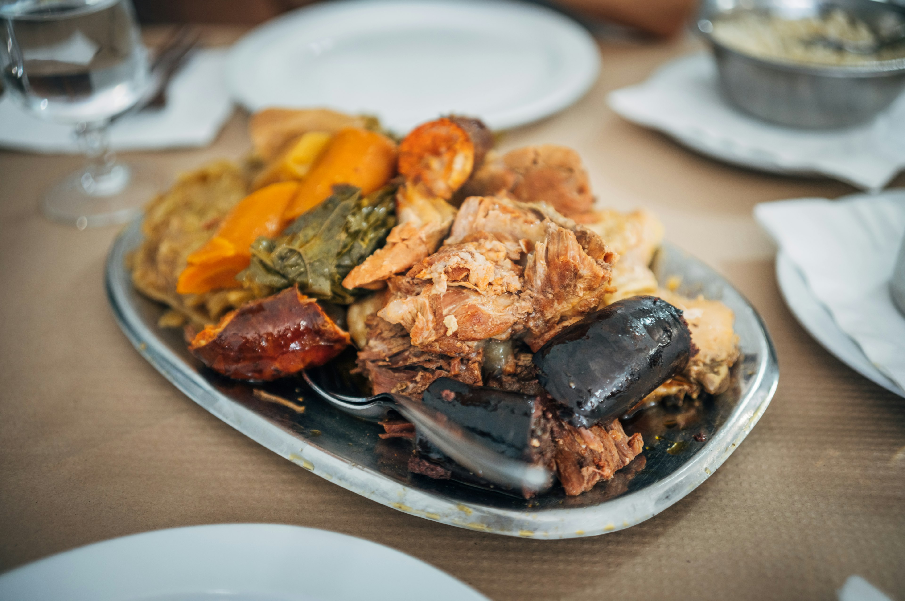 A dish of meat, taro, potatoes and other vegetables on a wooden table