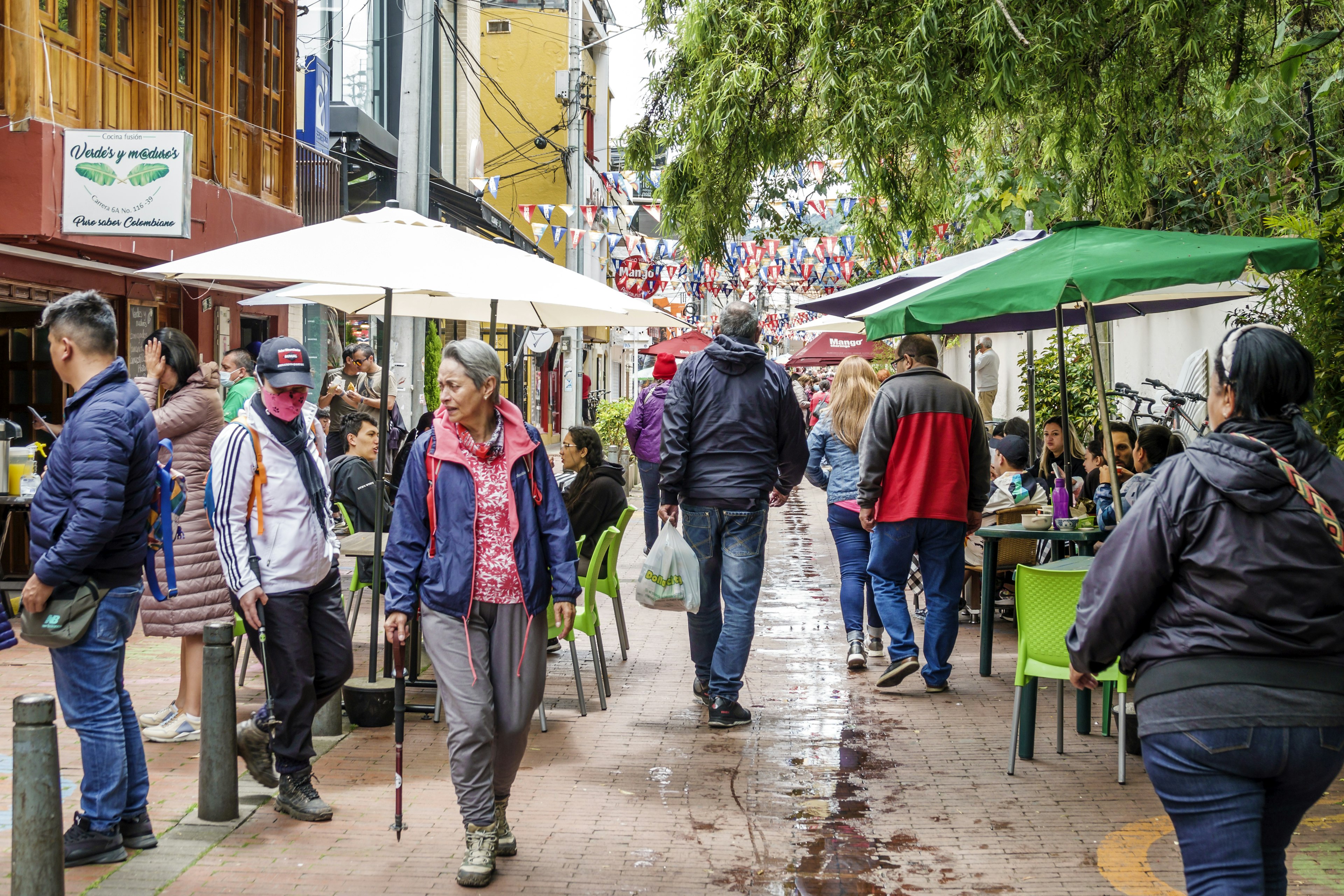 People walk past vendors at the Sunday flea market on a rainy afternoon in Usaquén, Bogotá, Colombia