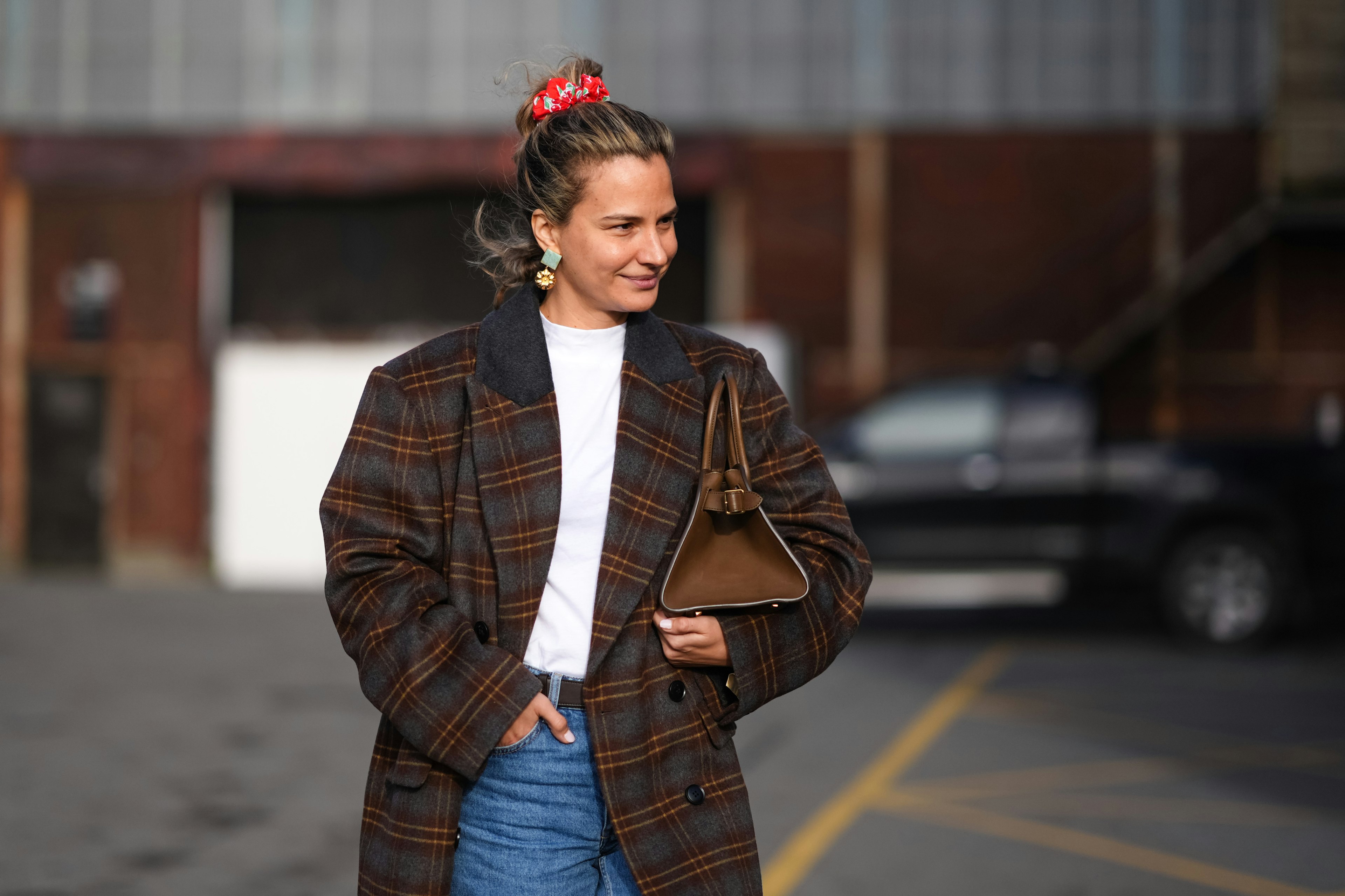 A woman wears a red hair scrunchie and a brown checkered / checked oversized blazer jacket in Copenhagen