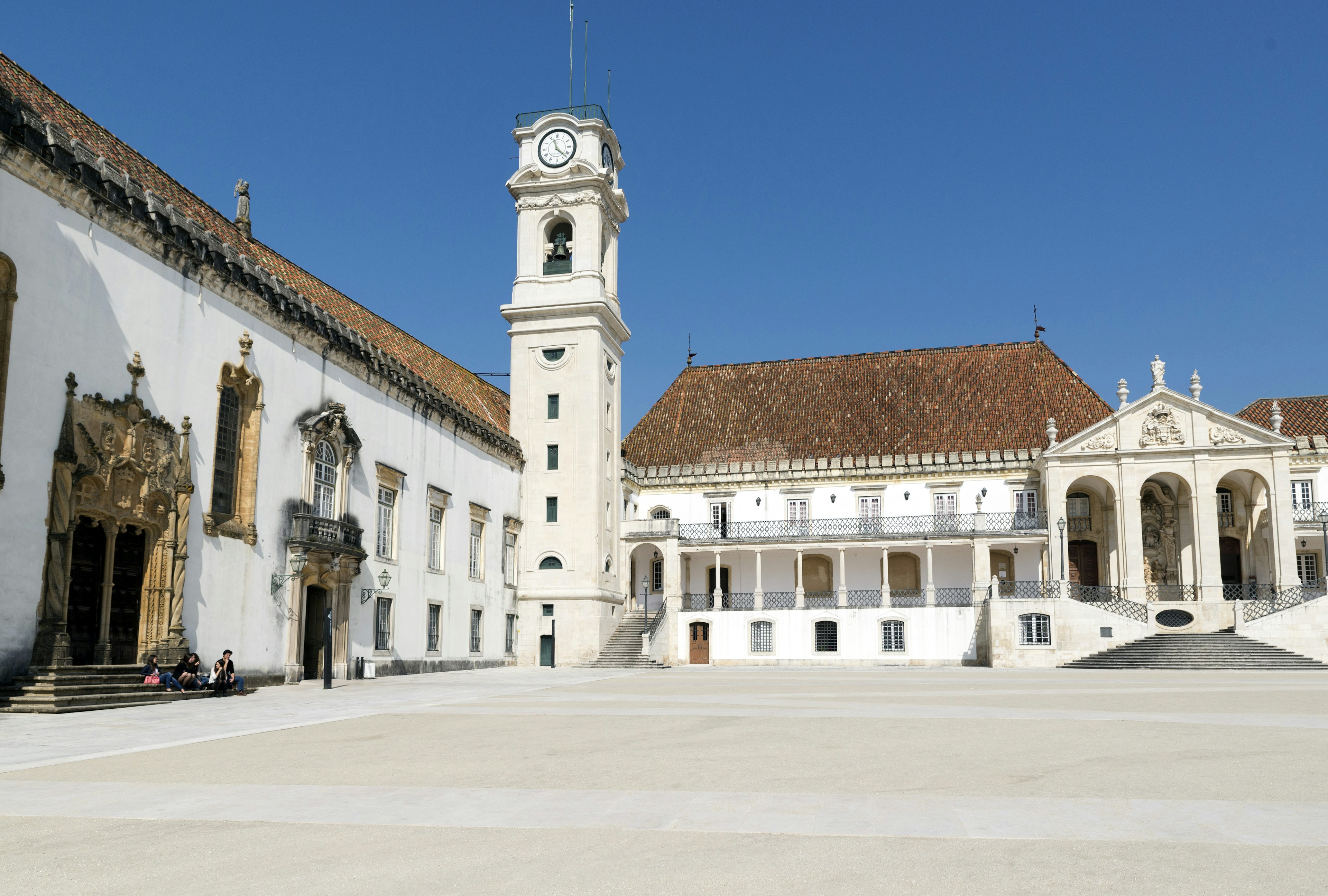 A large open city square surrounded by ancient buildings and a large clocktower