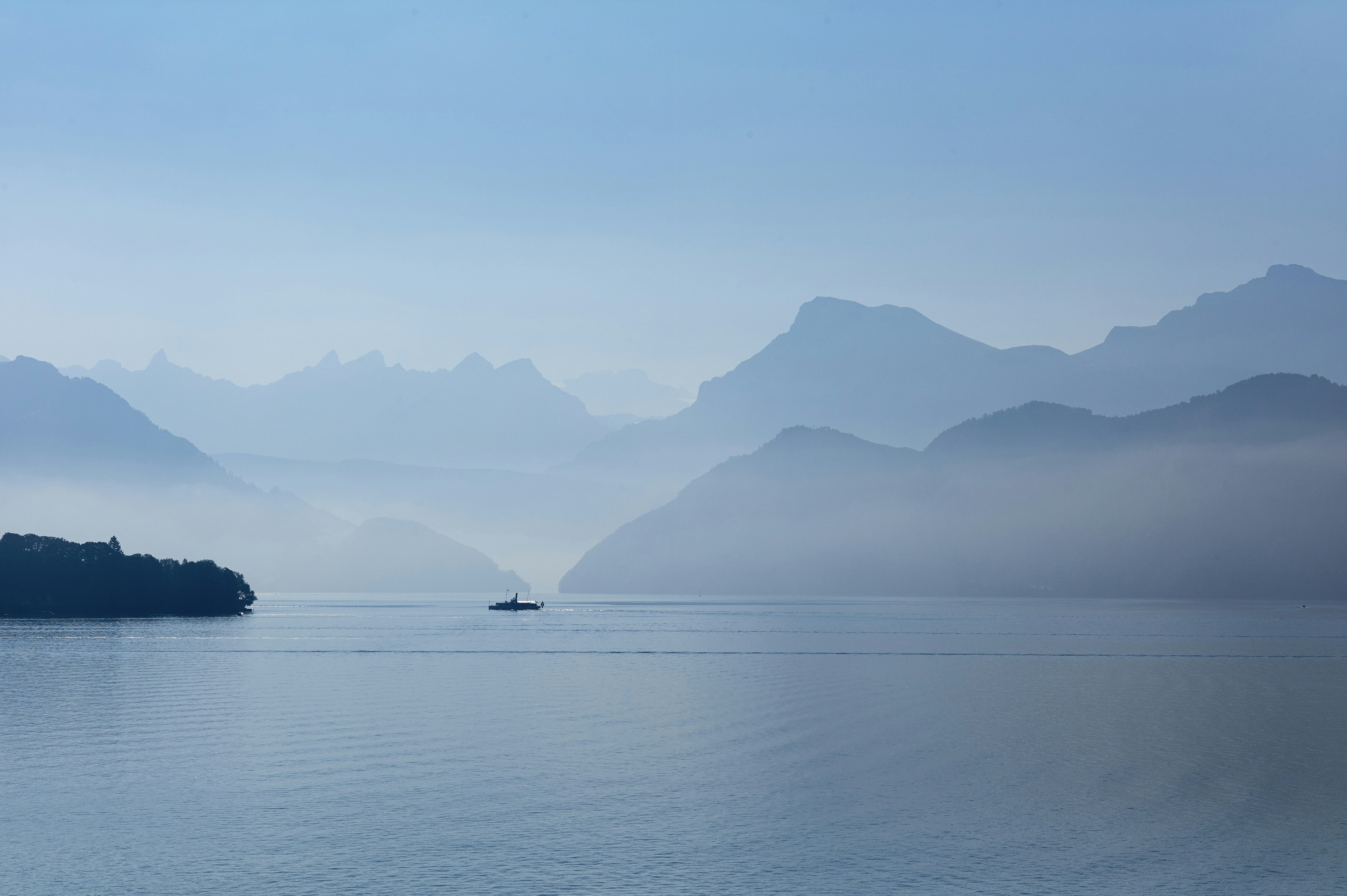 A boat on the blue waters of Lake Lucerne, surrounded by mist-covered mountains