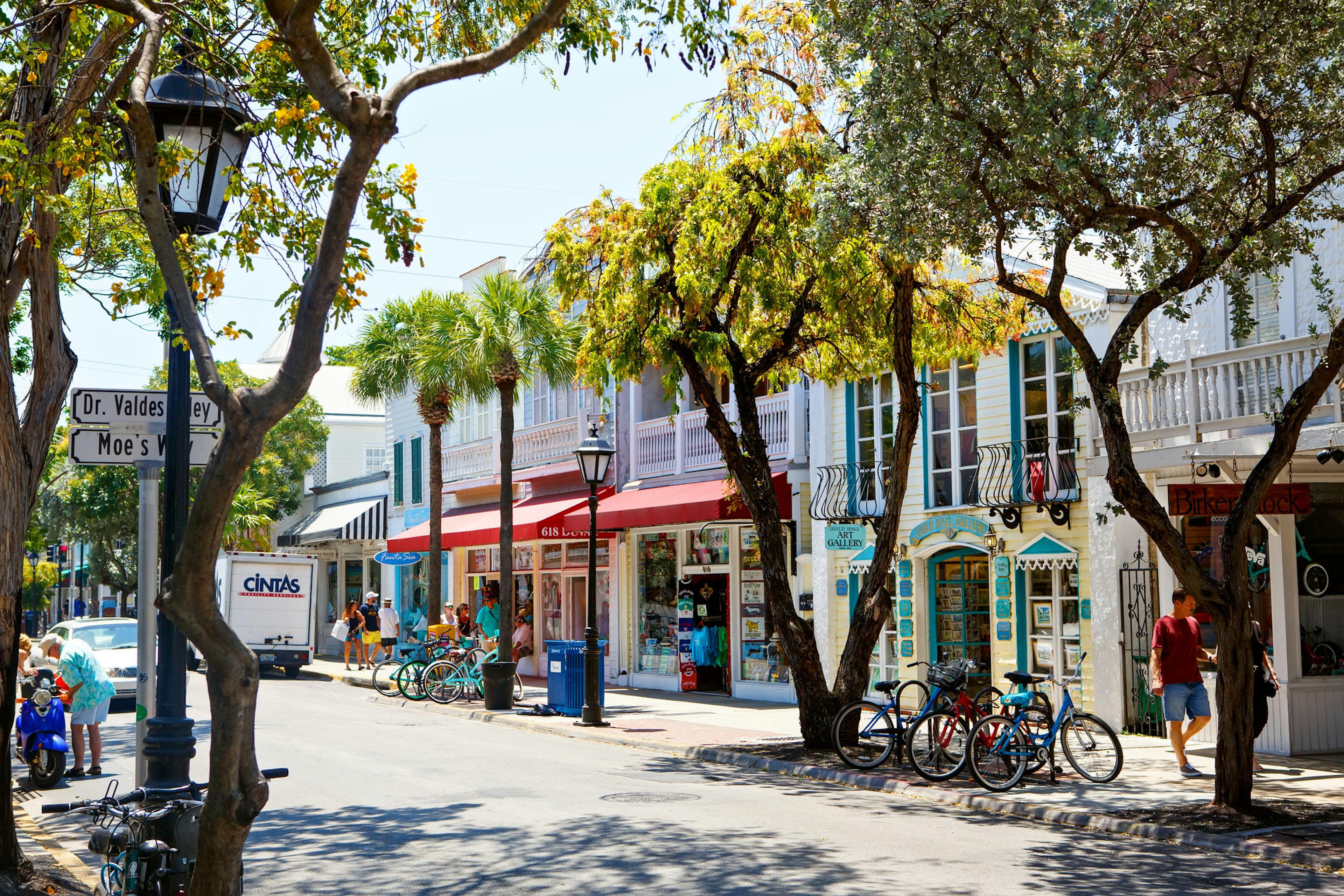 Pastel-colored quaint storefronts line a street