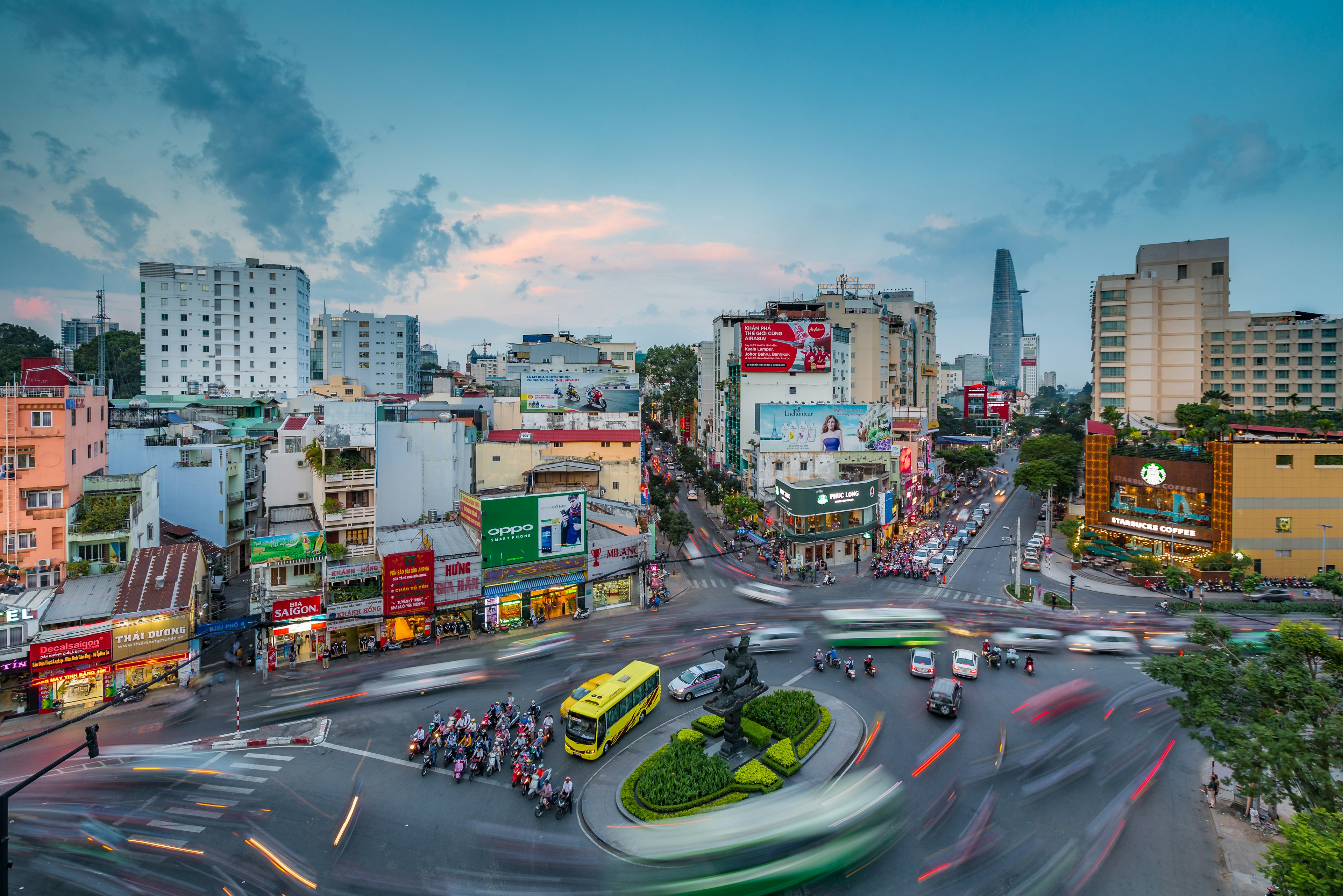 Motorbike traffic blurs as it moves around a roundabout in a built-up city