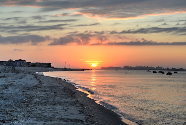 An empty beach as the sun sets casting an orange glow across the sky