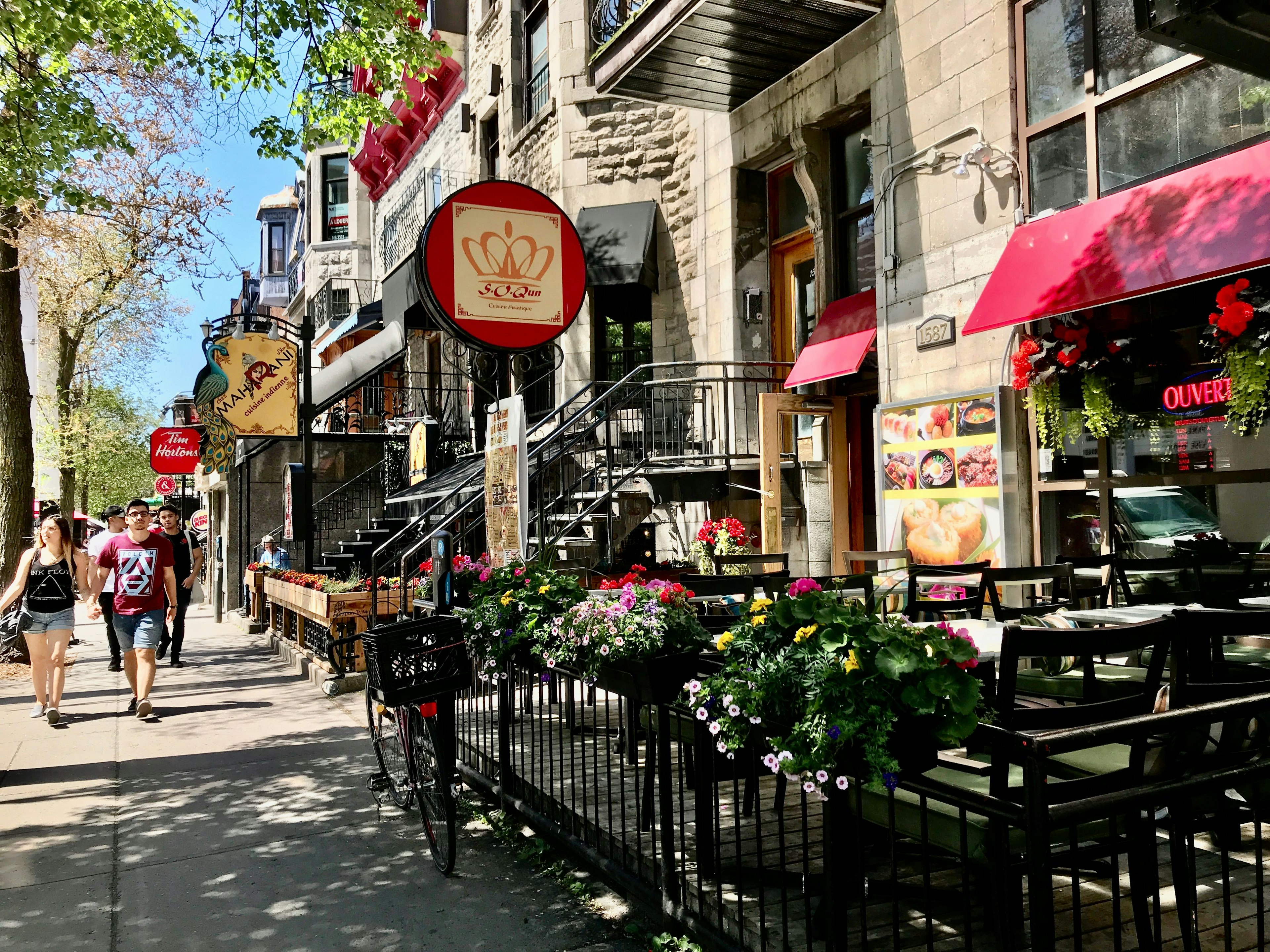 People walk by restaurants on the Rue Saint-Denis, the central artery of the Latin Quarter (Quartier Latin), on a May day, Montréal, Québec, Canada