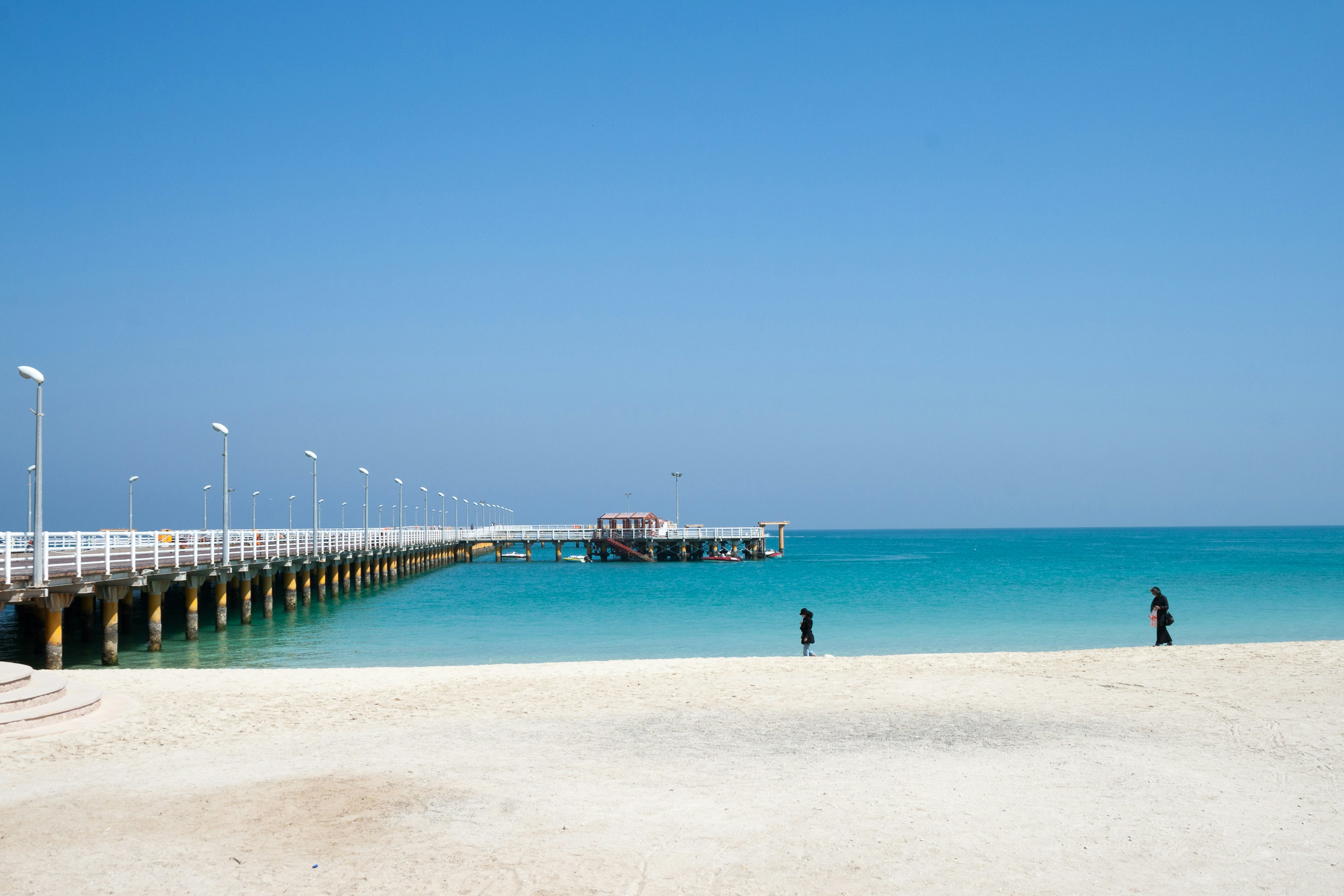 The Grand Recreational Pier of Kish Island, Iran, jutting from the sandy beach area into the azure-blue waters of the Gulf