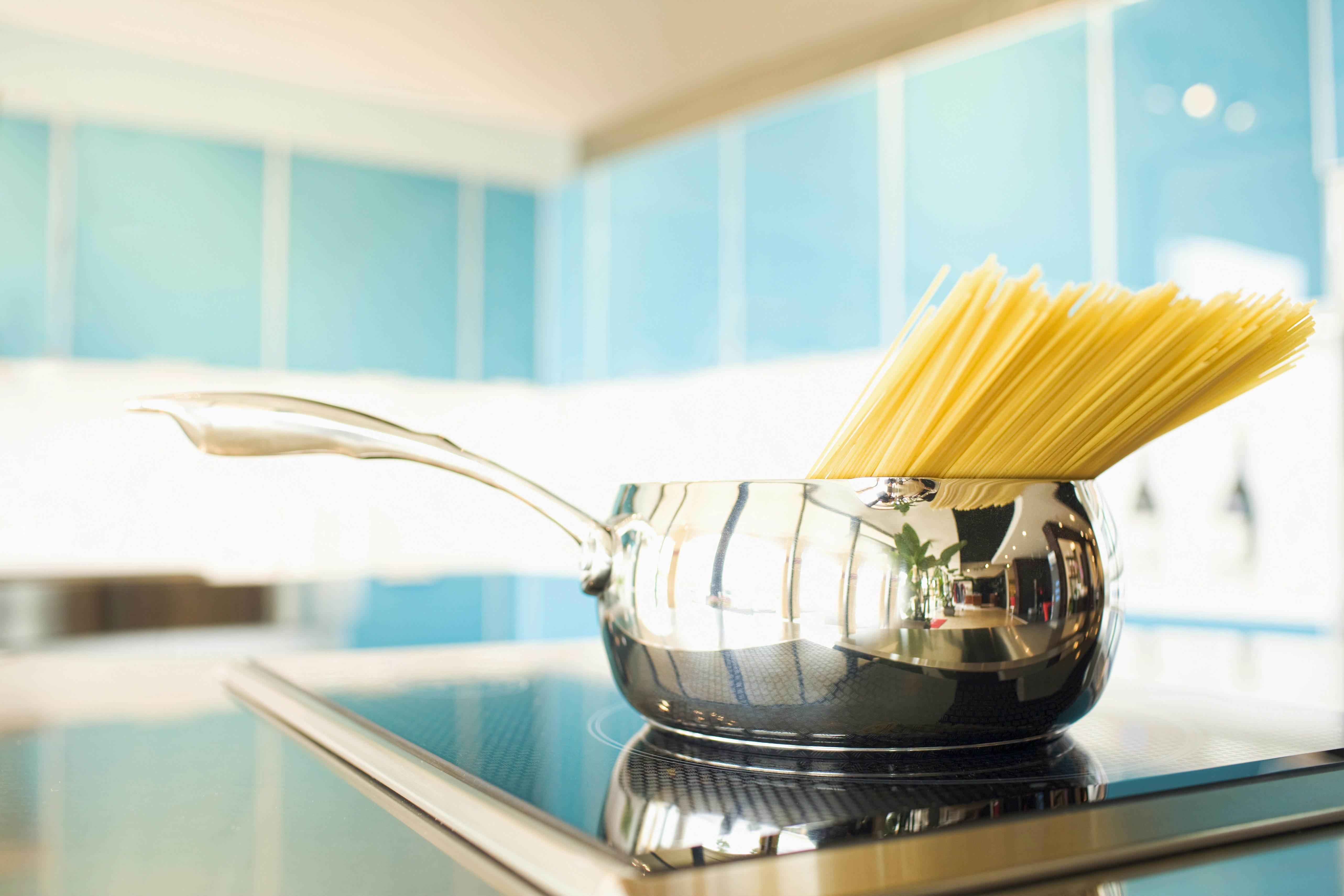 Pasta in pot on stove, teal tile background