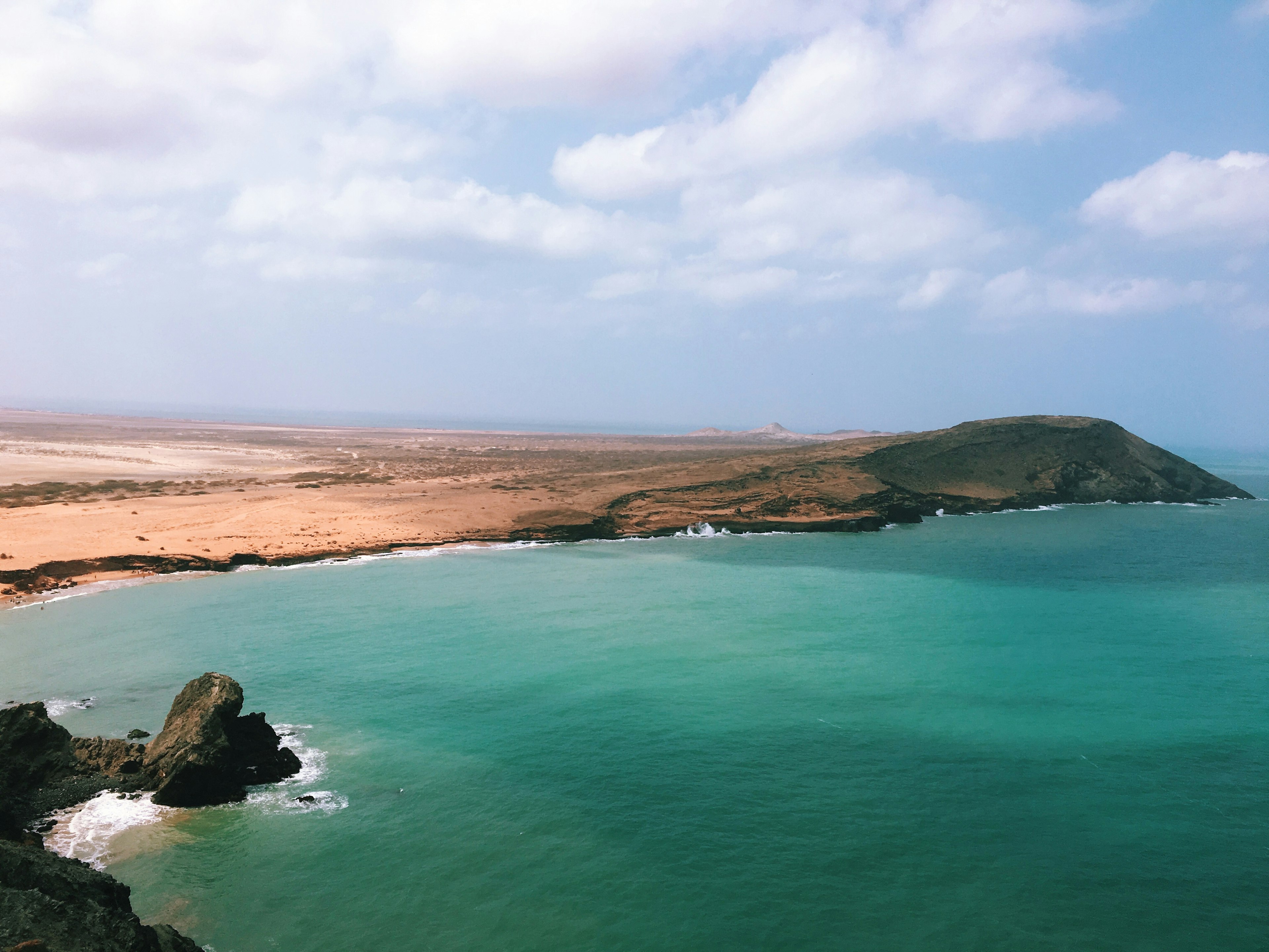 An aerial view of turquoise ocean hitting a desert coastline in La Guajira, Colombia