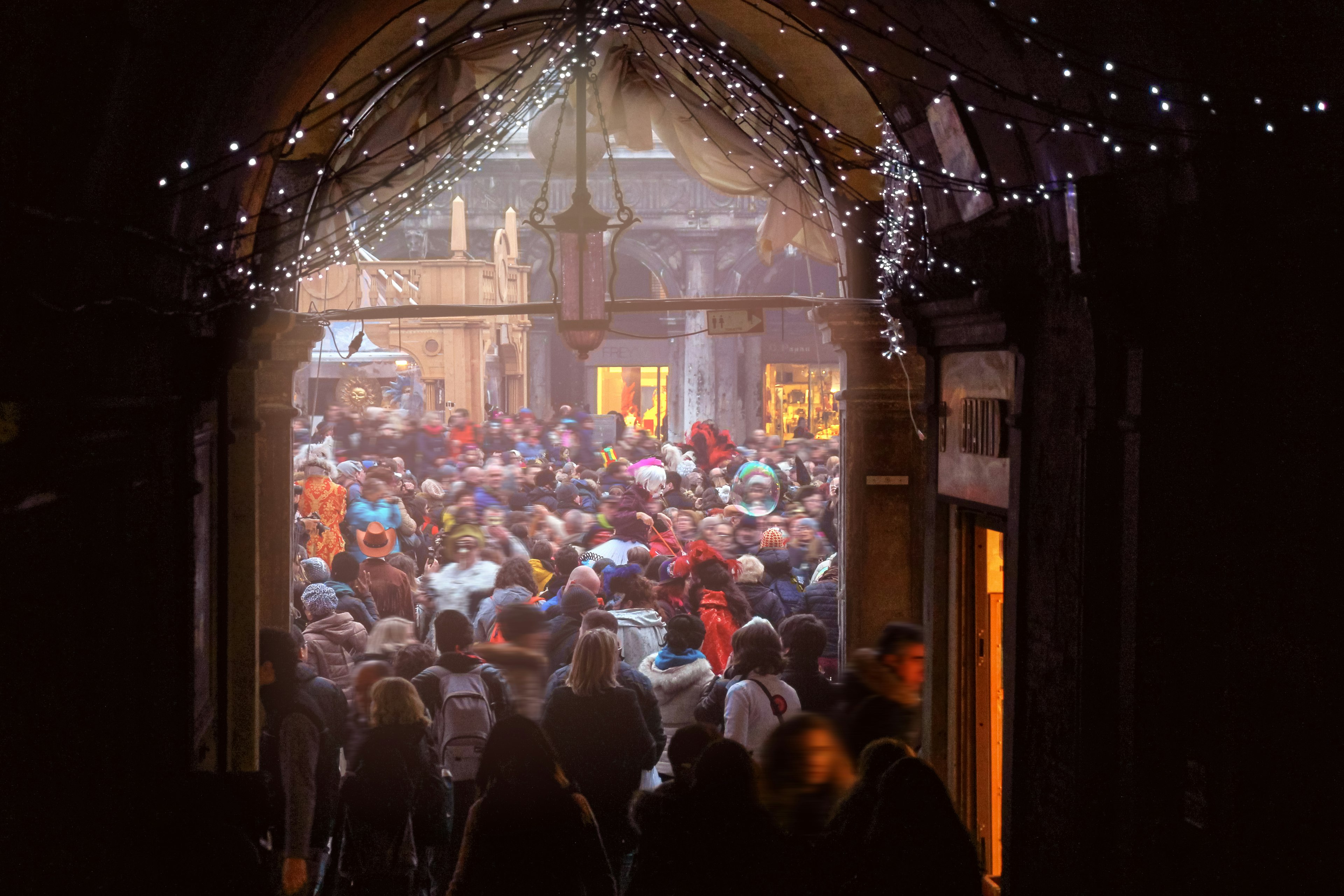 Crowds fill a street and archway in Venice