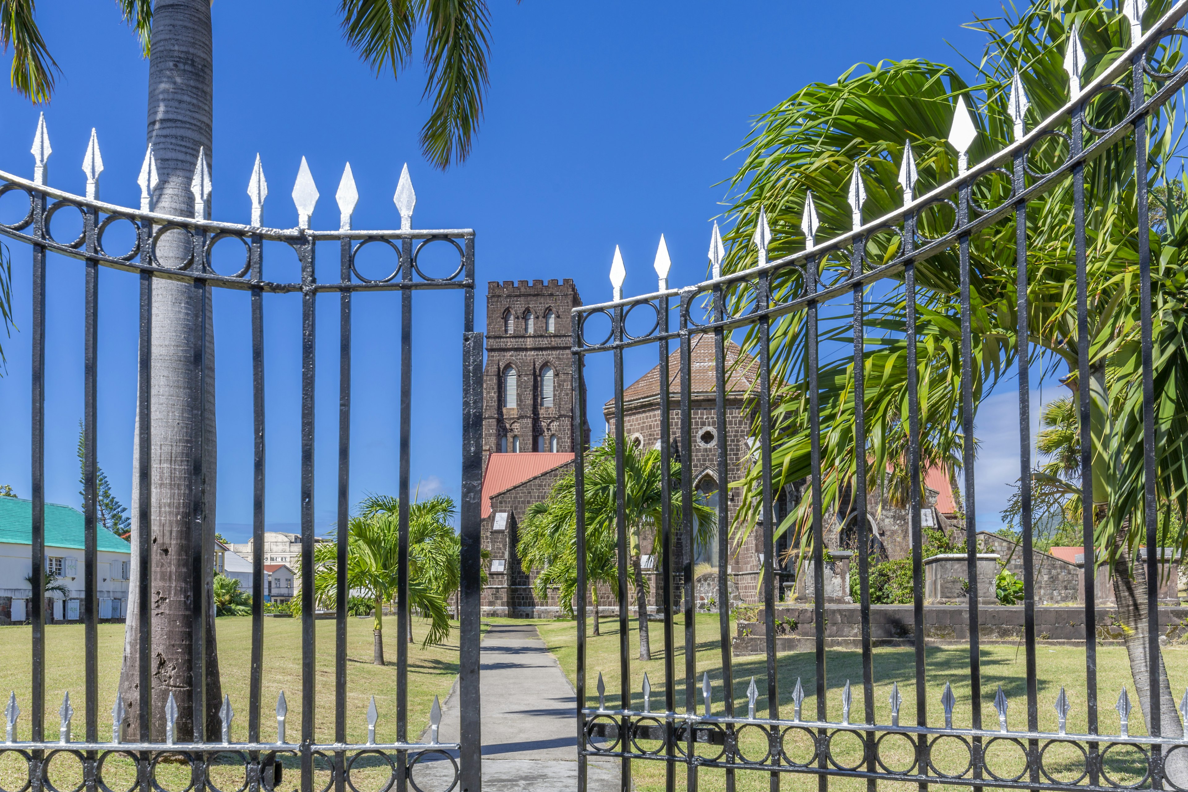 Iron gates are partially open in front of an old stone church