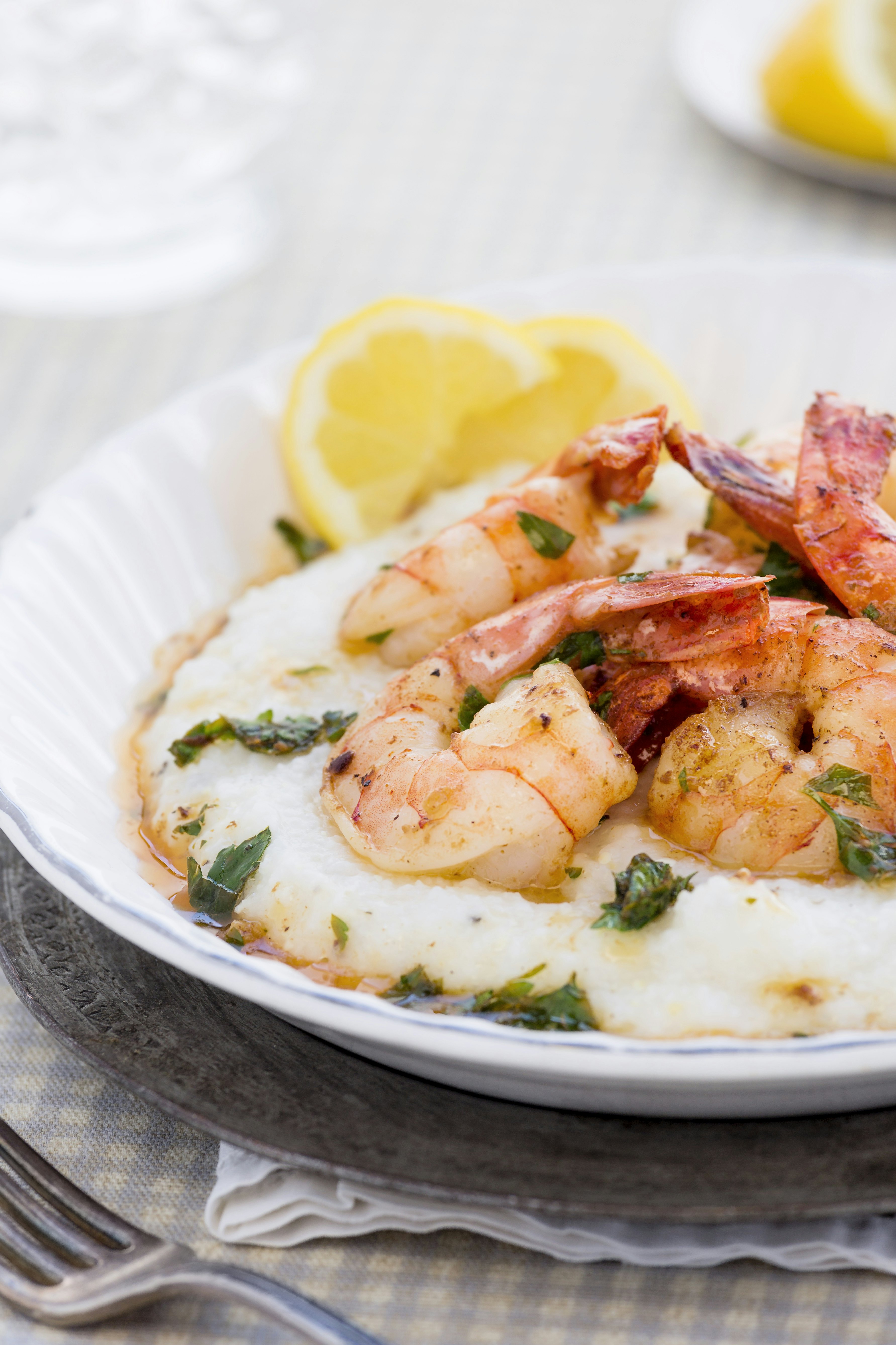 Close-up shot of a bowl of shrimp and grits, with lemon wedges on the side