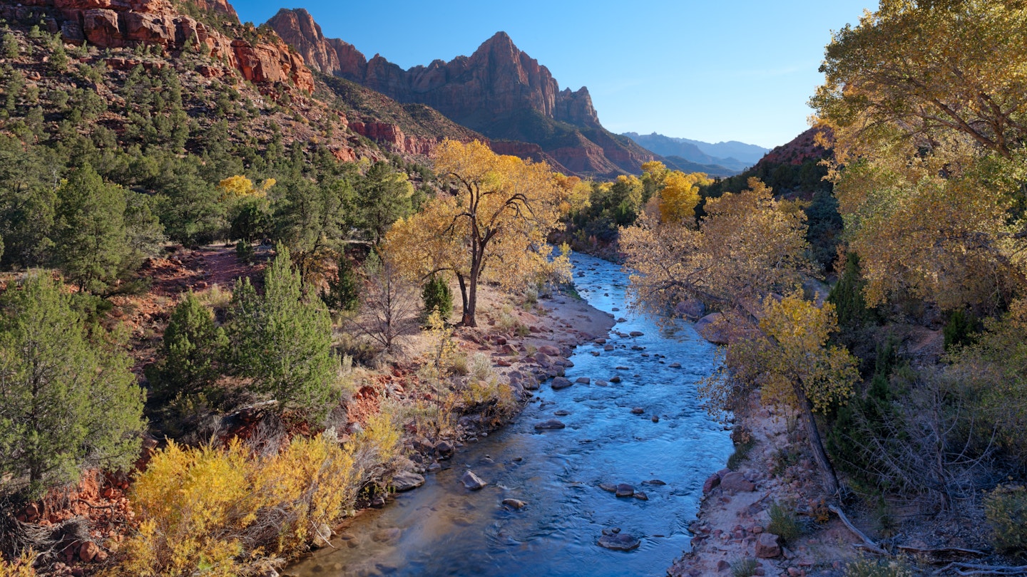 174975261
Autumn; Beauty In Nature; Blue; Canyon; Clear Sky; Cliff; Color Image; Day; Famous Place; Flowing Water; Horizontal; International Landmark; Landscape; Mountain; National Park; Nature; No People; Outdoors; Photography; Red Rocks; River; Rock - Object; Scenics - Nature; Sky; Southern USA; Southwest USA; Springdale - Utah; Stream - Flowing Water; Sunny; The Watchman; Tranquil Scene; Travel; USA; Utah; Virgin River; Yellow; Zion National Park;
The Virgin River flows through a red rocky valley with autumn colours.