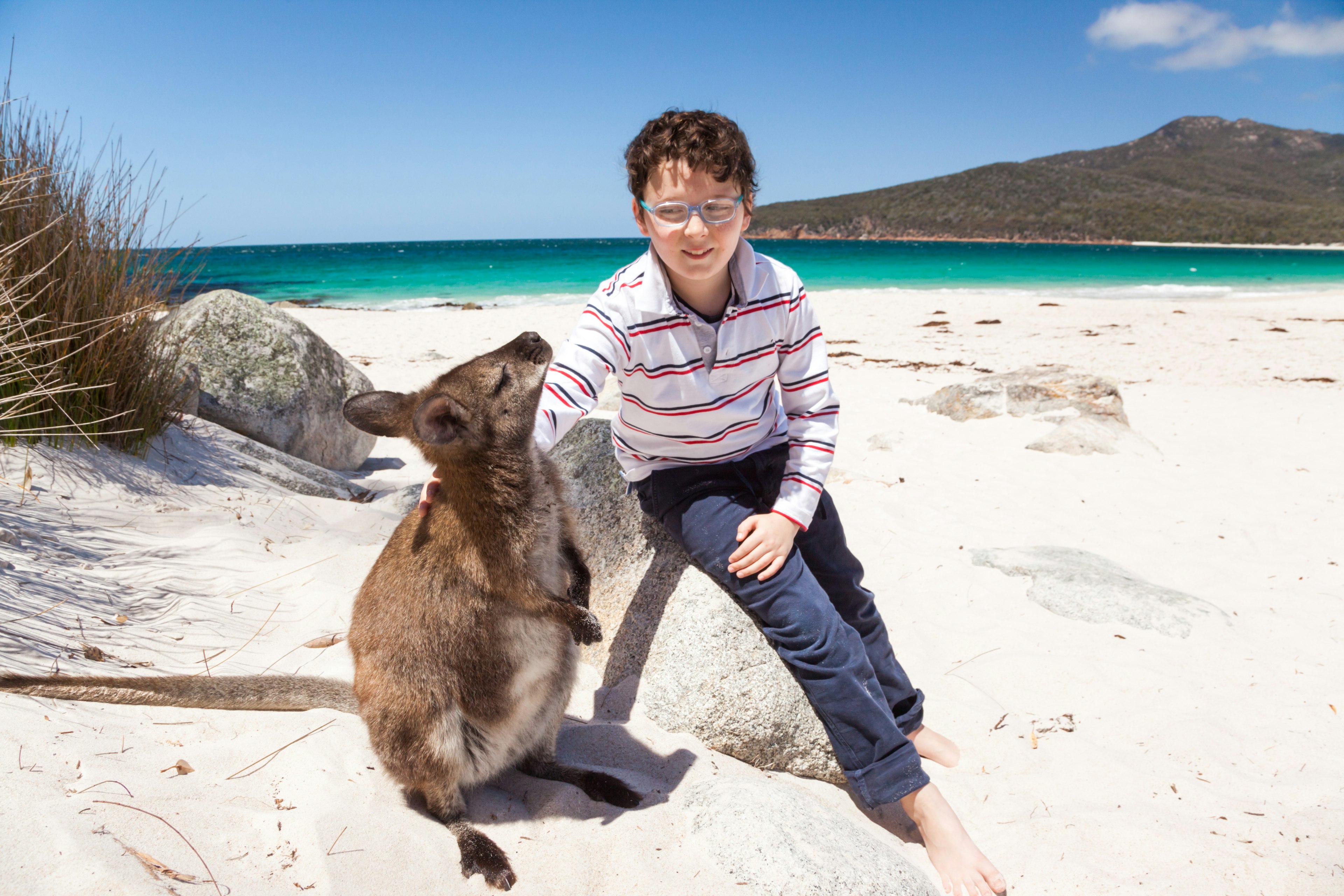 Child with little wallaby pet at Wineglass Bay beach.