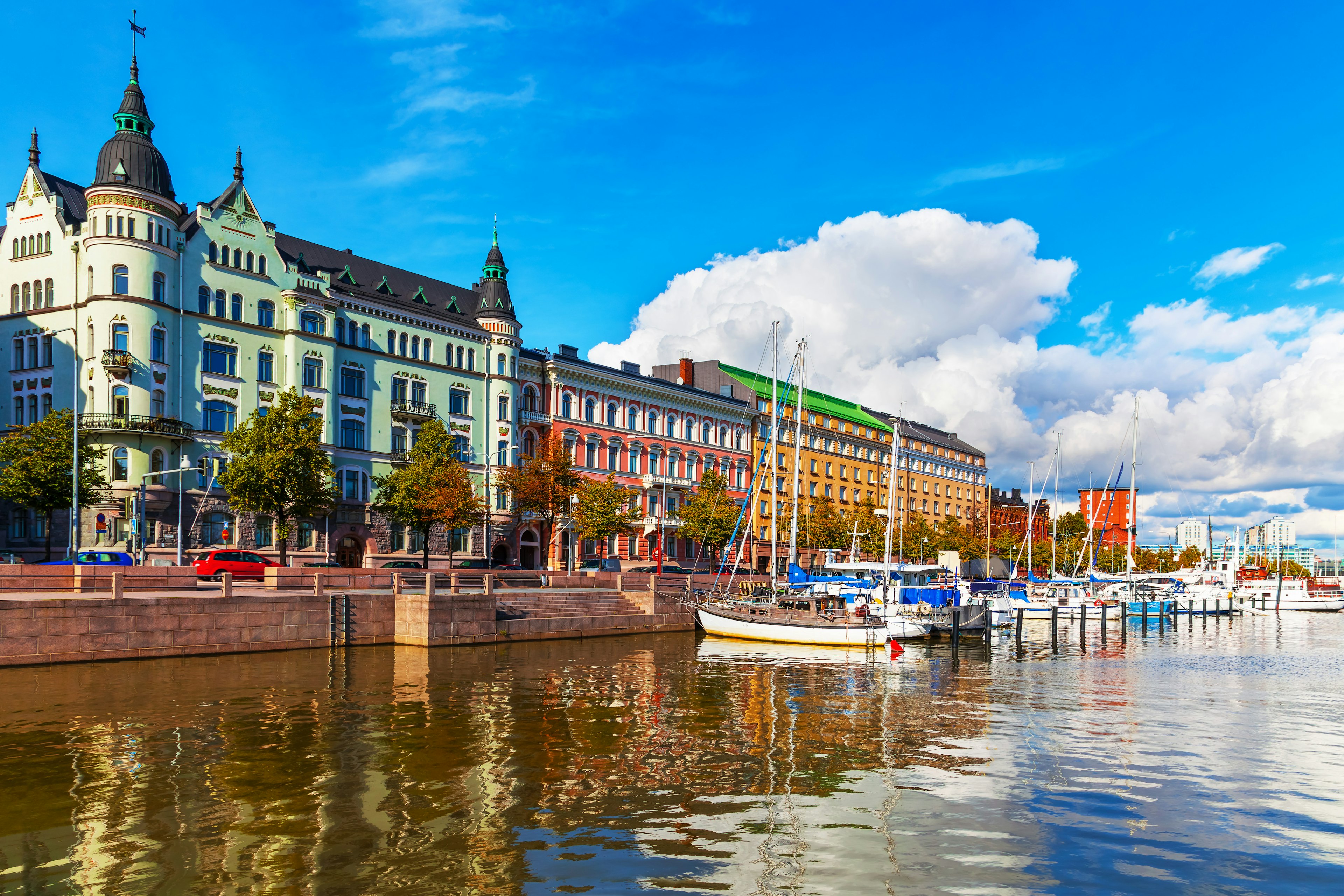 Old Town pier in Helsinki, Finland, with colorful building reflections on the water below and clouds in the sky above.