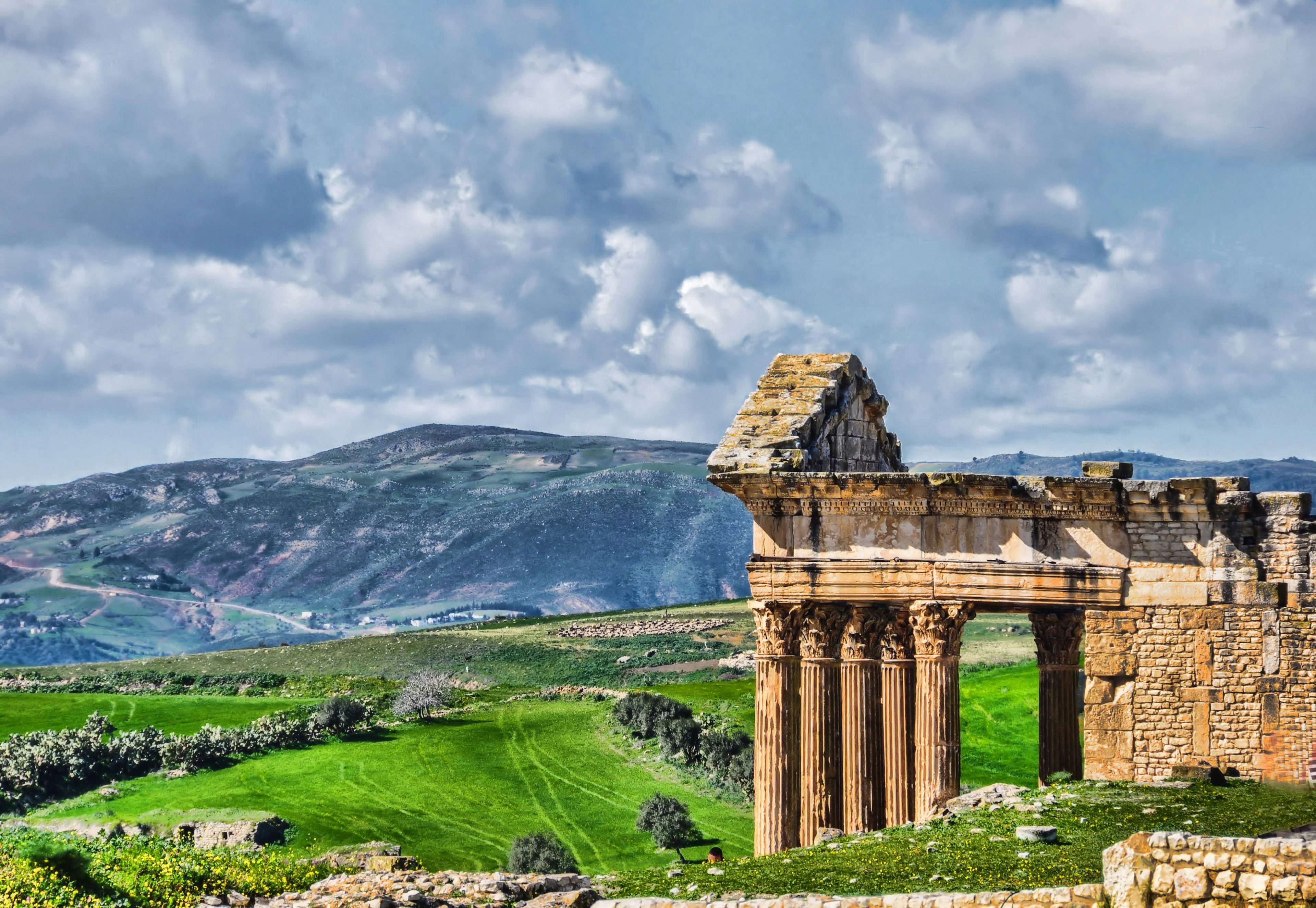 View of the Roman Temple of Jupiter at the archaeological site of Dougga, with mountains in the background