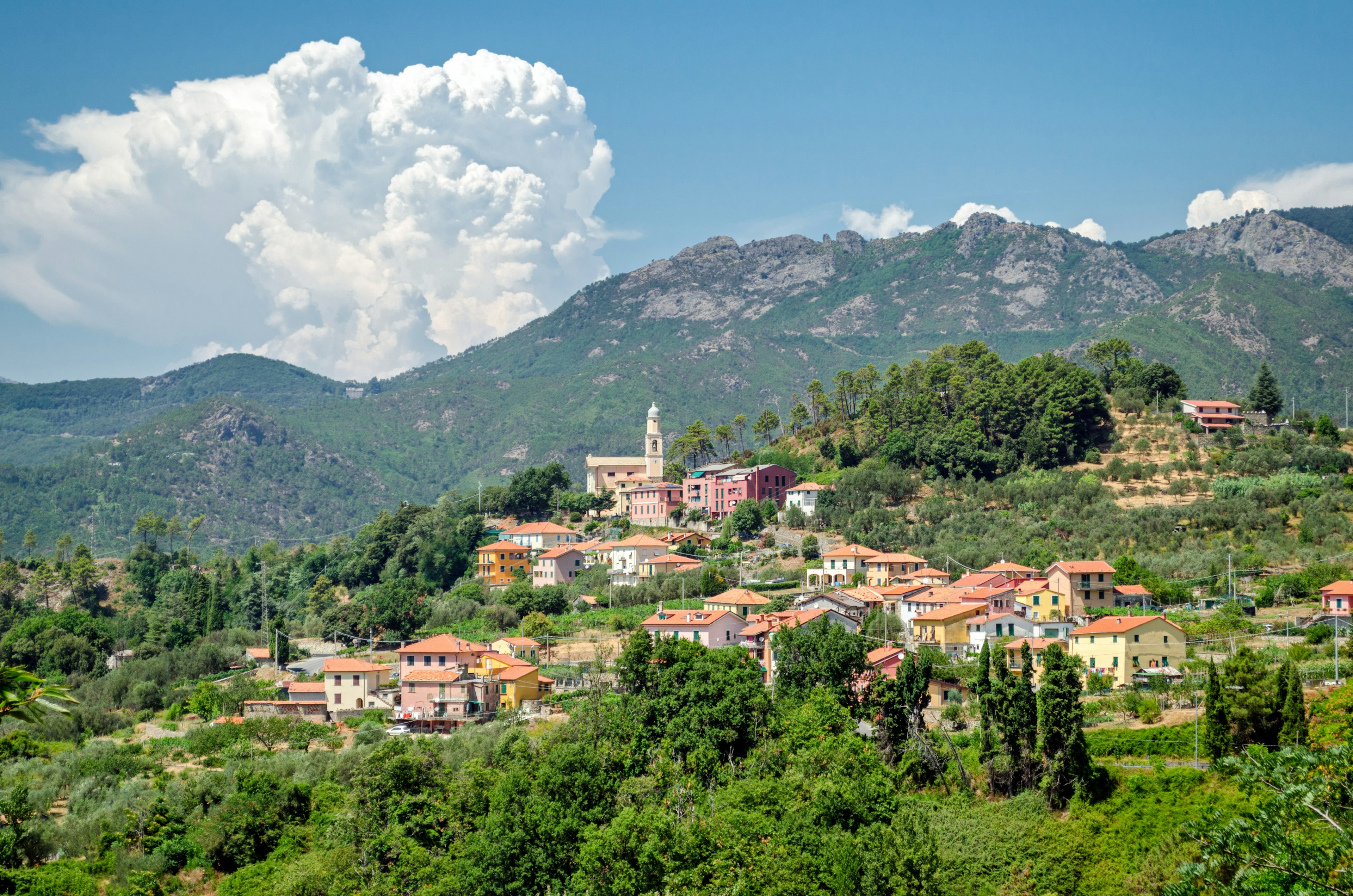 The pastel-coloured buildings of one of Framura's hamlets sit on a hillside.