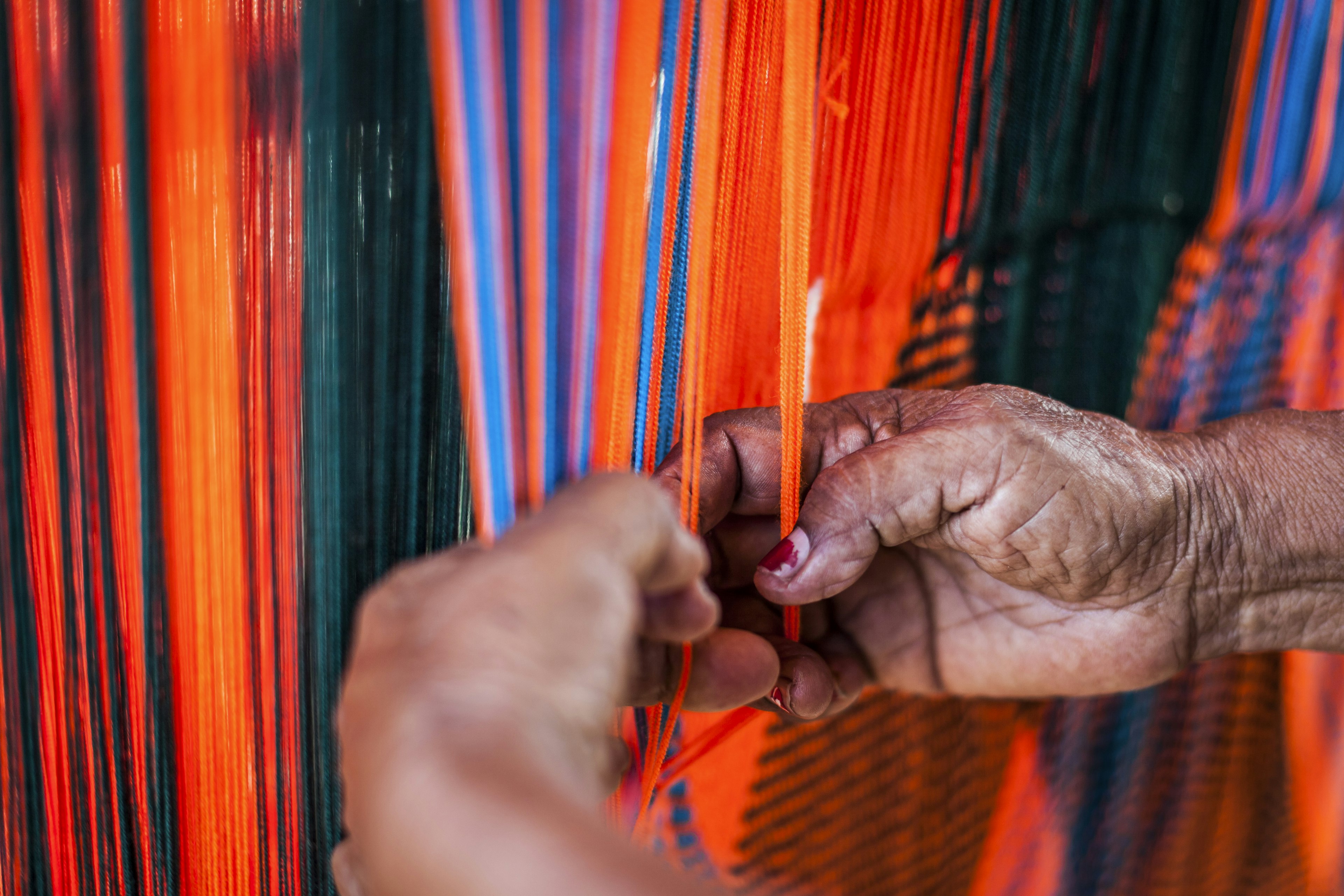 Close-up of a woman's hands weaving a chinchorro (Colombian hammock) in the town of Uribia.