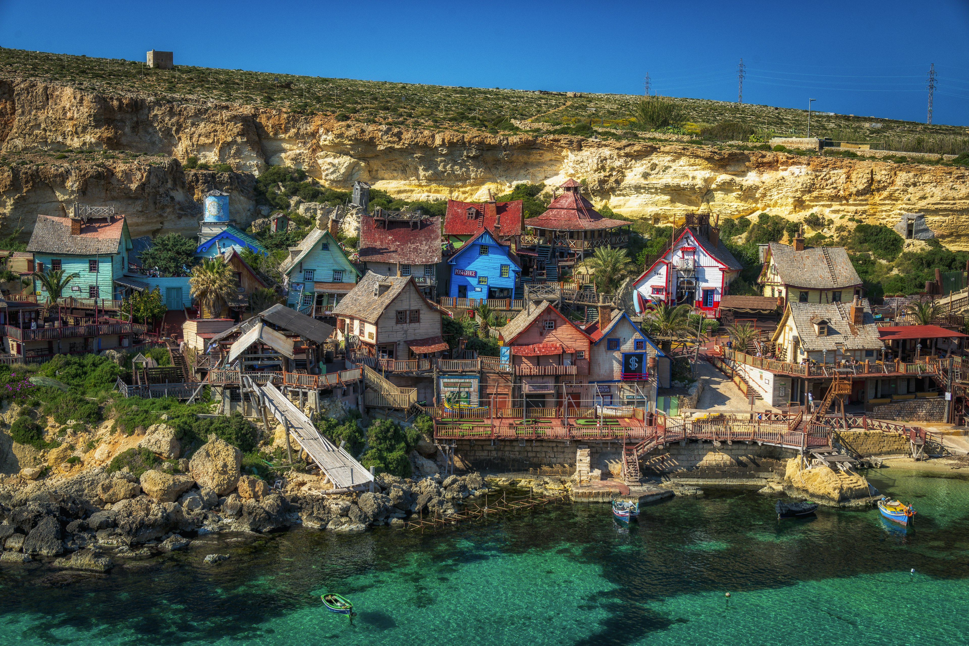 Popeye Village, colorful buildings by a body of clear water.