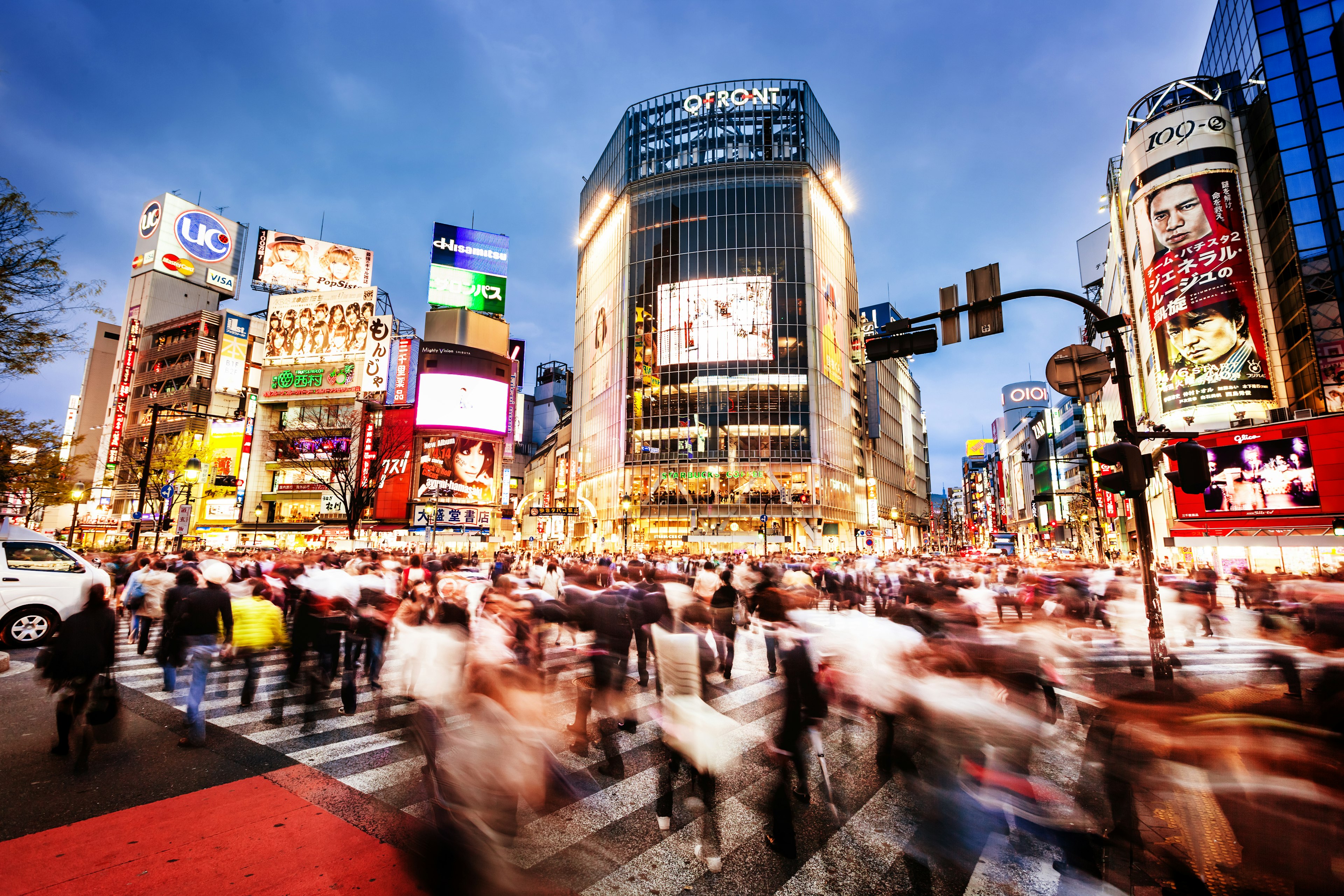 The world famous crossroad in Shibuya, Tokyo with commuters at dusk.