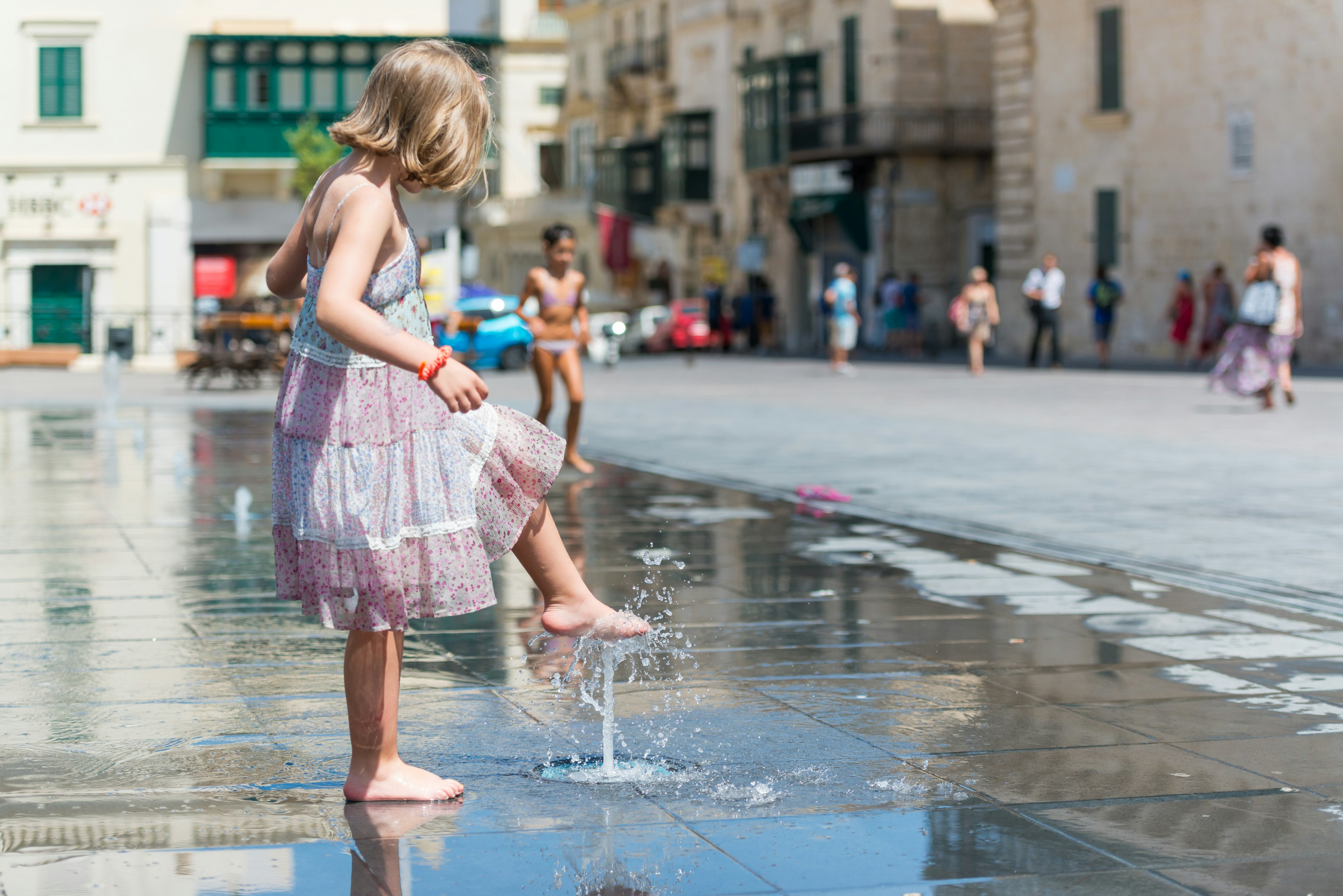 Young girl old cooling her legs with water from pop jet fountains in St. George's Square.