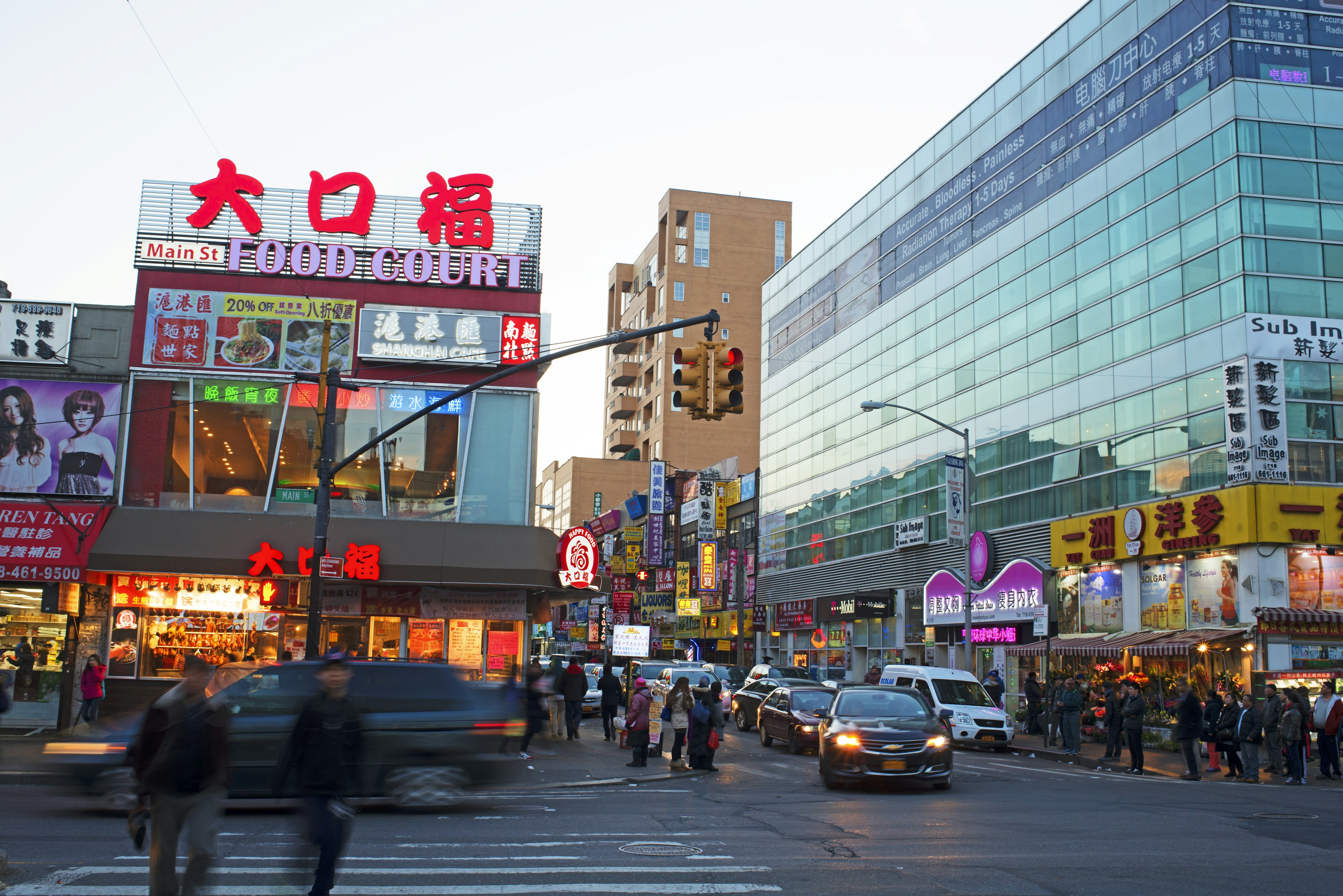 A lively street full of restaurants with neon signs lit up at dusk