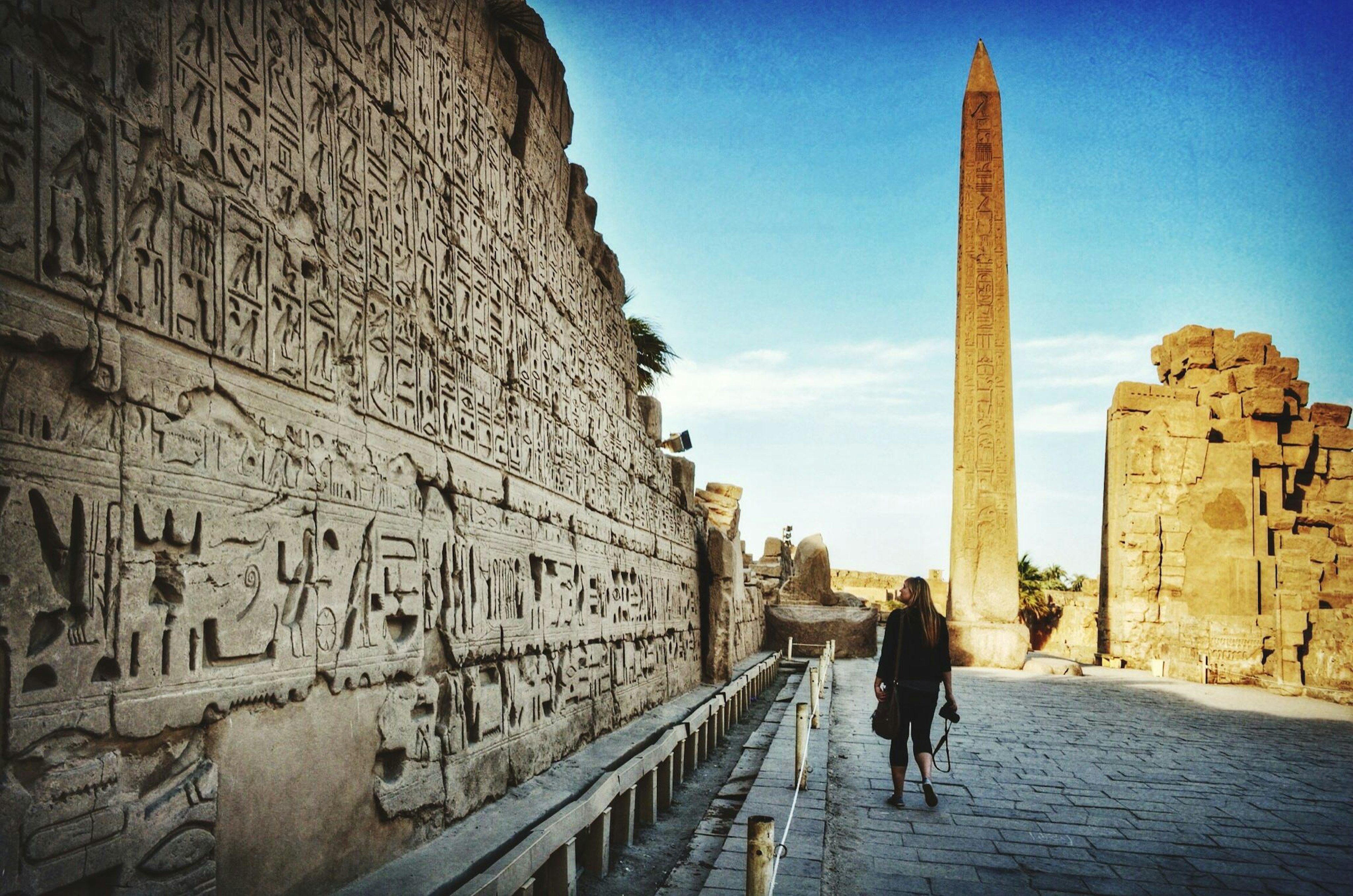 Woman walks near a wall of hieroglyphics at Karnak Temple, Luxor, Egypt