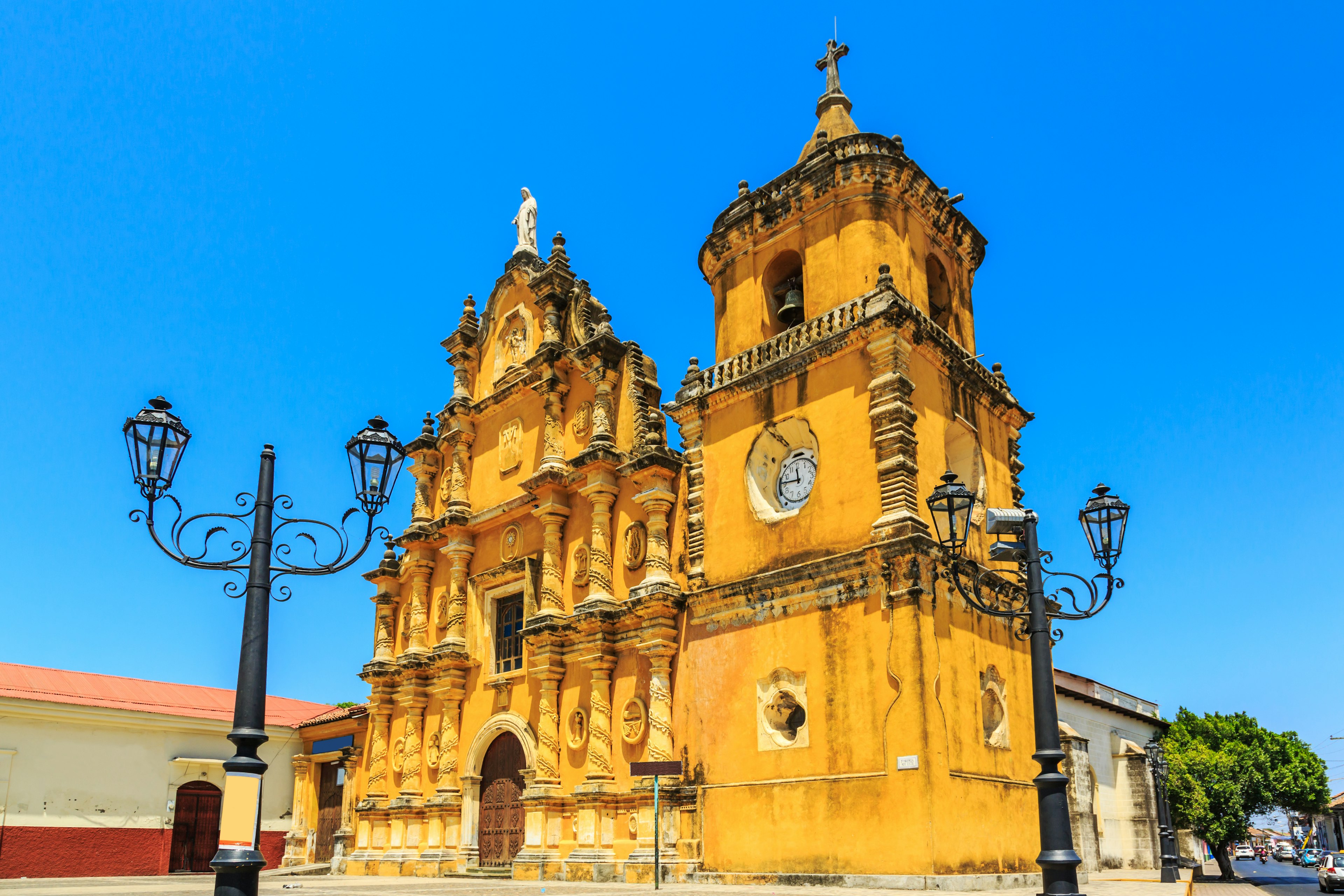 A baroque-style bright yellow church on a corner in the city of León.