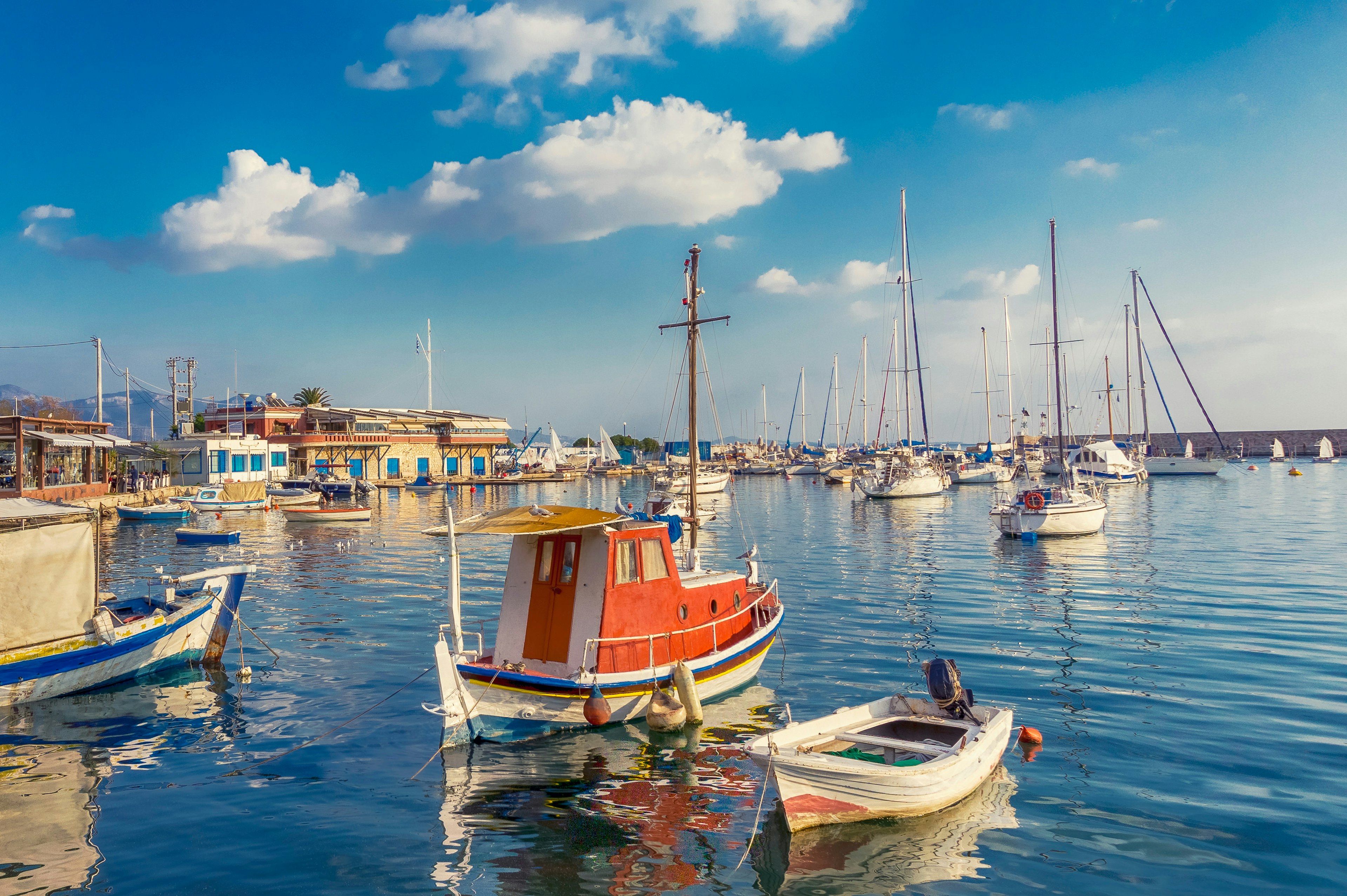 Sailboats float in a harbor near Piraeus, Greece, on a sunny day.