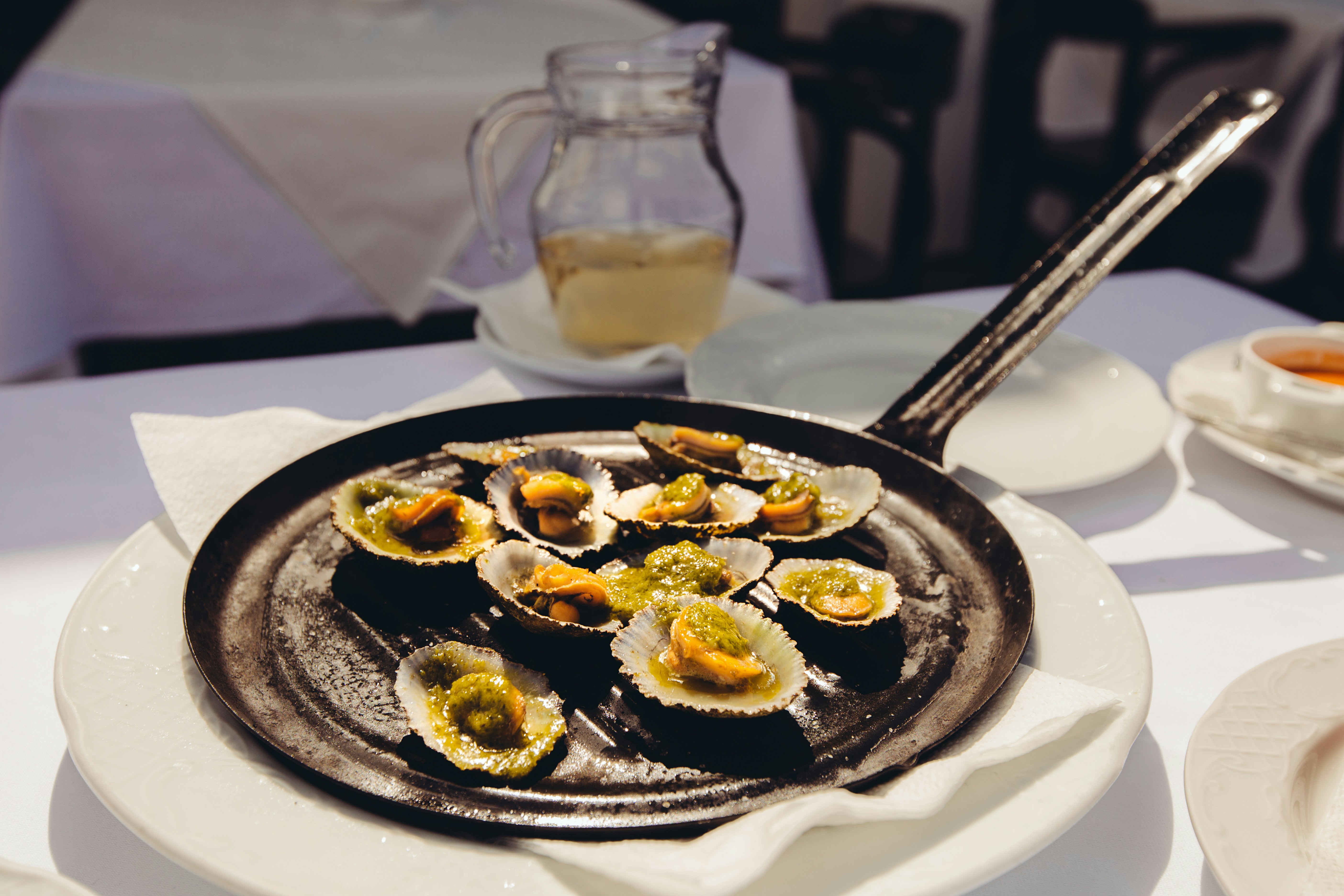 Canarian grilled limpets served on the frying pan with green mojo (typical Canarian sauce) and lemon.