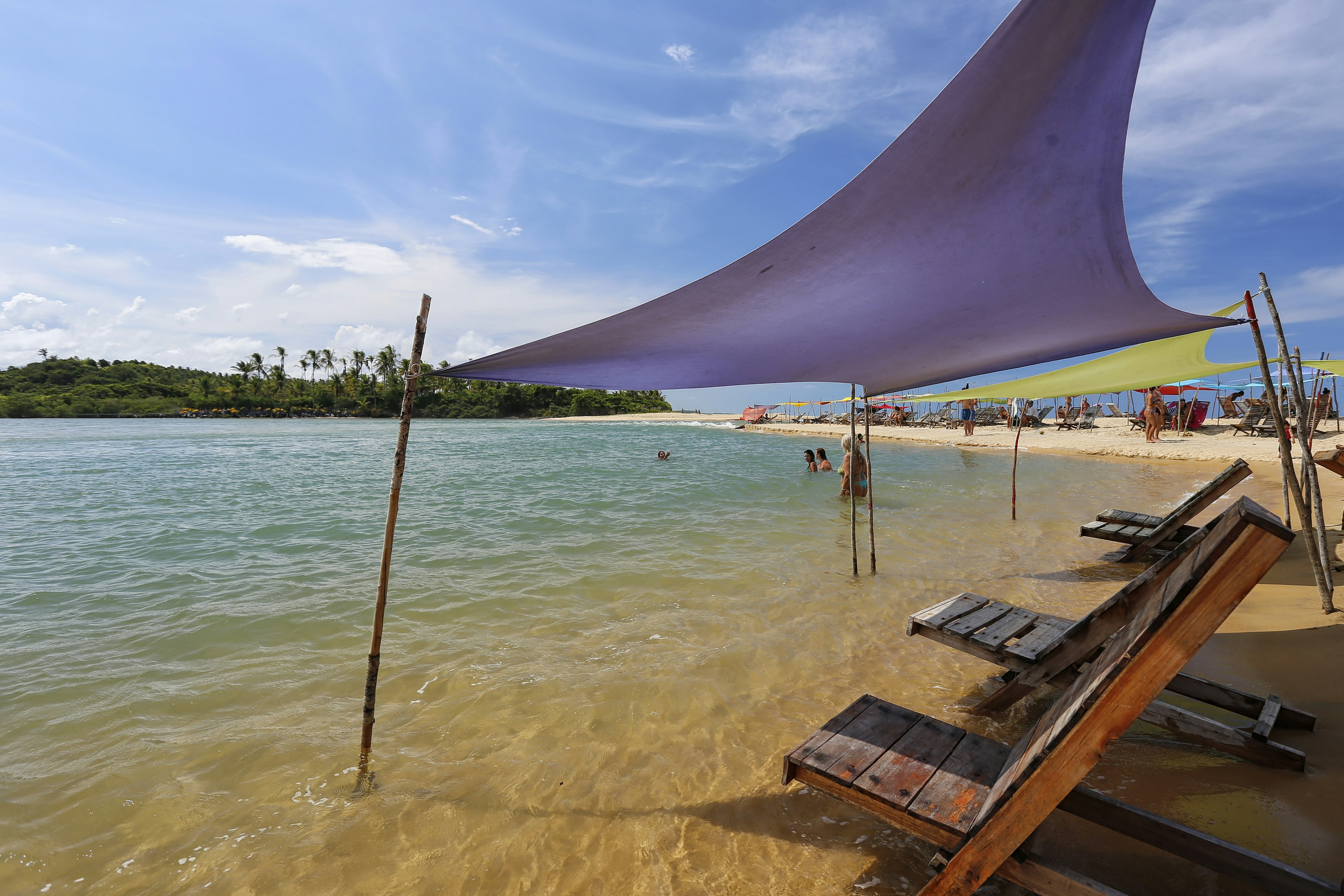 Chairs in the water where the river meets the sea in Caraiva.