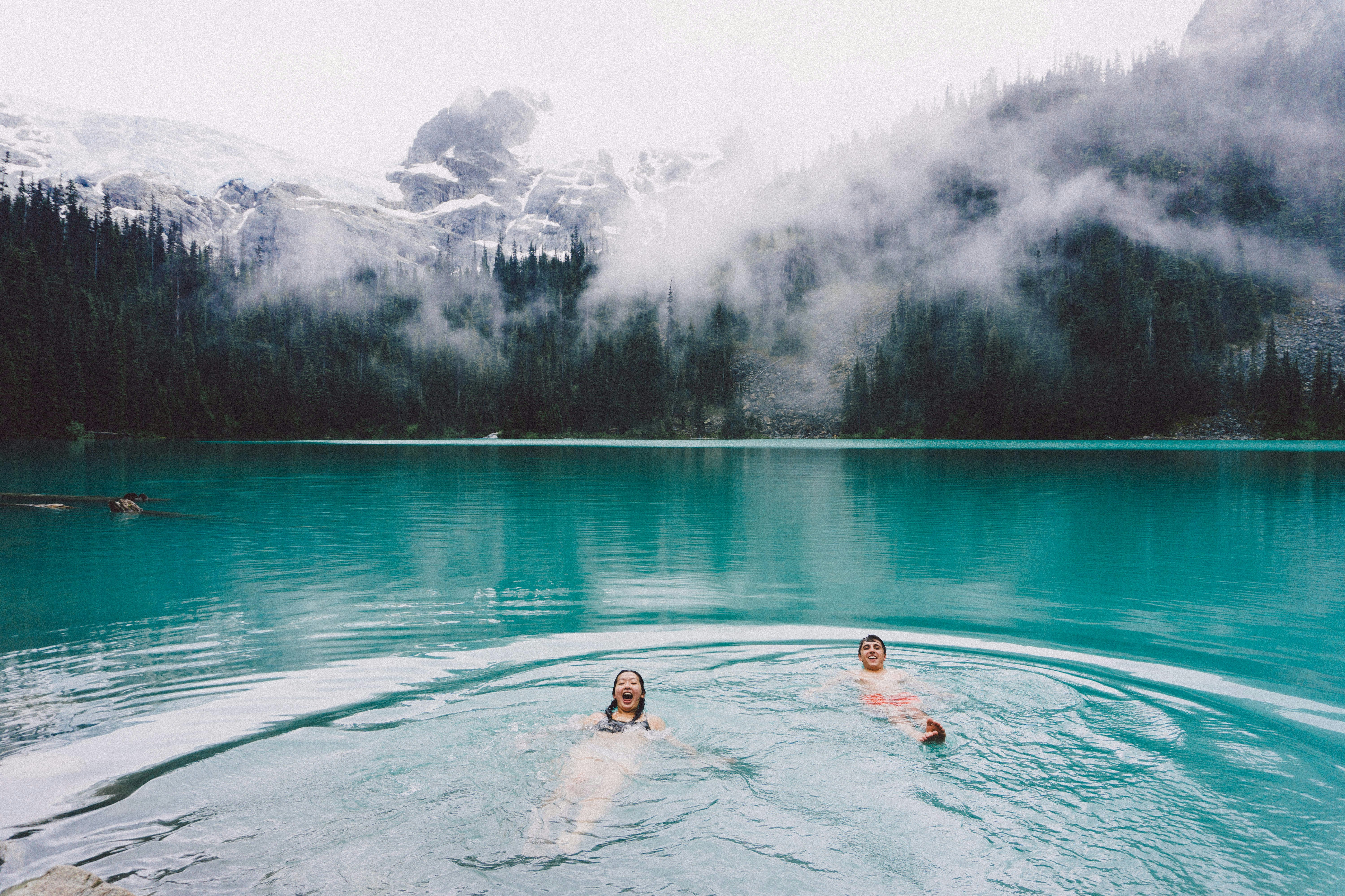 Couple swimming in a lake with mountains in the background