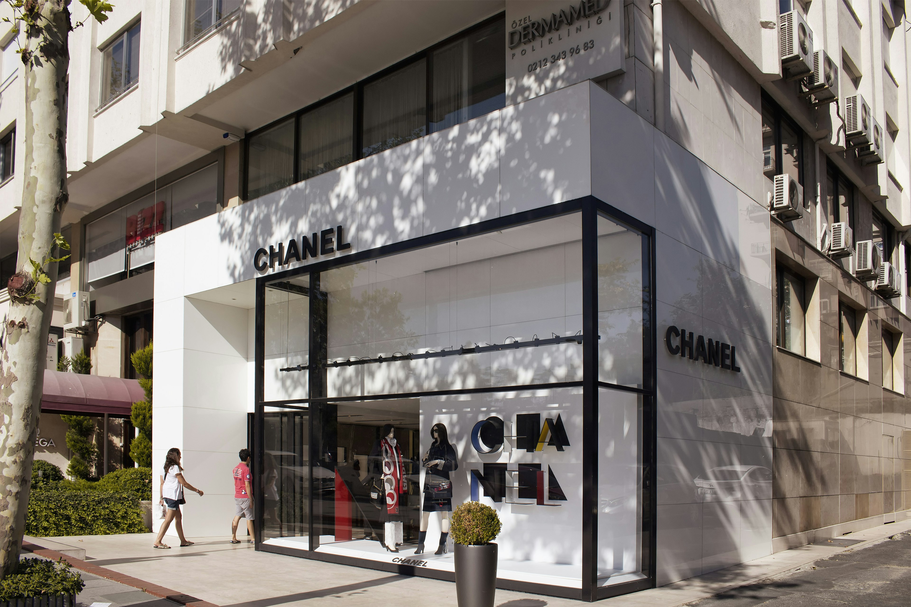 Two people are walking in to a Chanel store in the upmarket district of şԳٲşı in Istanbul. The store has an elegant black and white facade.