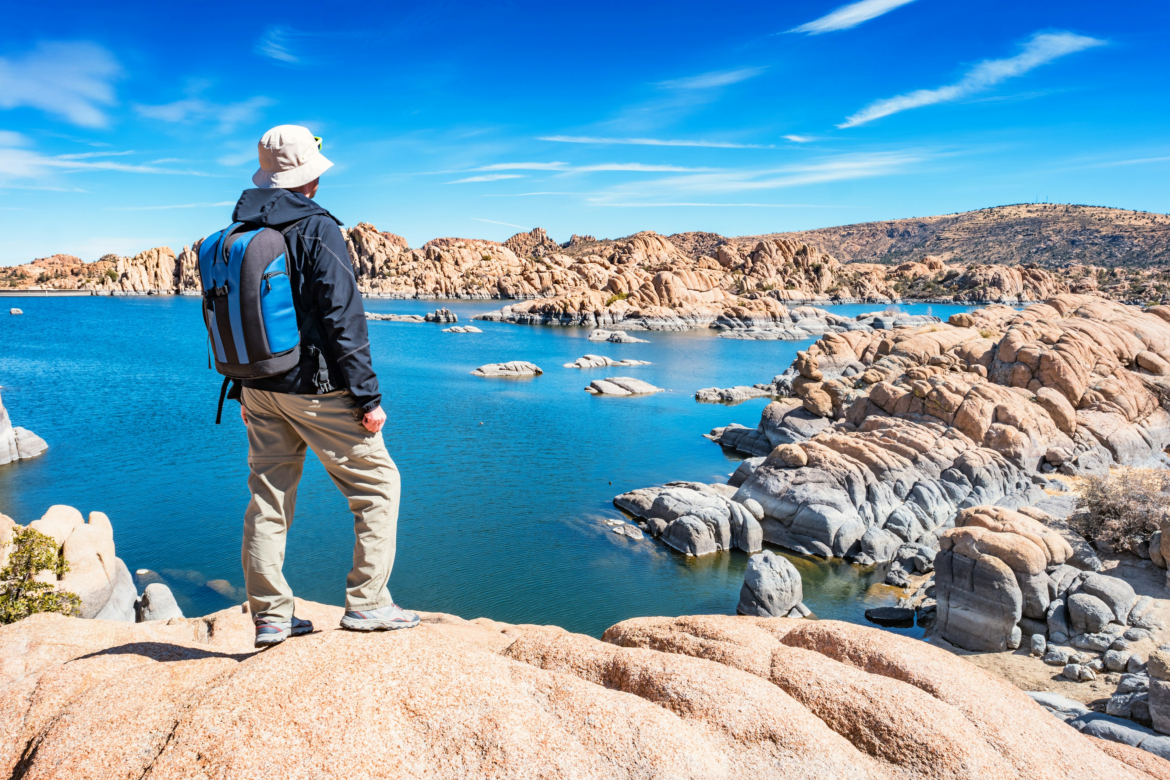 Male hiker with a backpack looking at Watson Lake in Prescott.