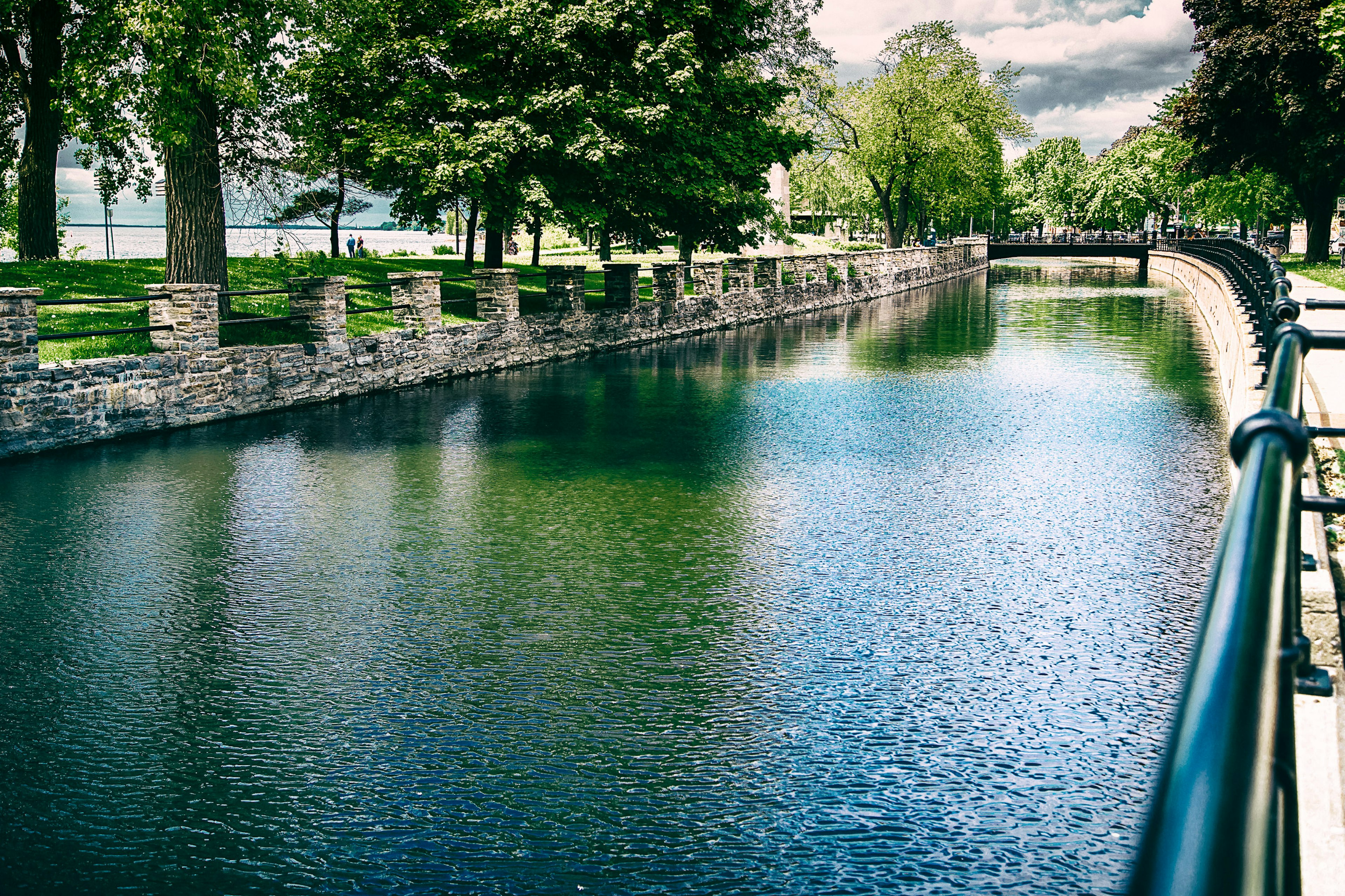 A lovely green canal curves into the distance with trees reflected in the water