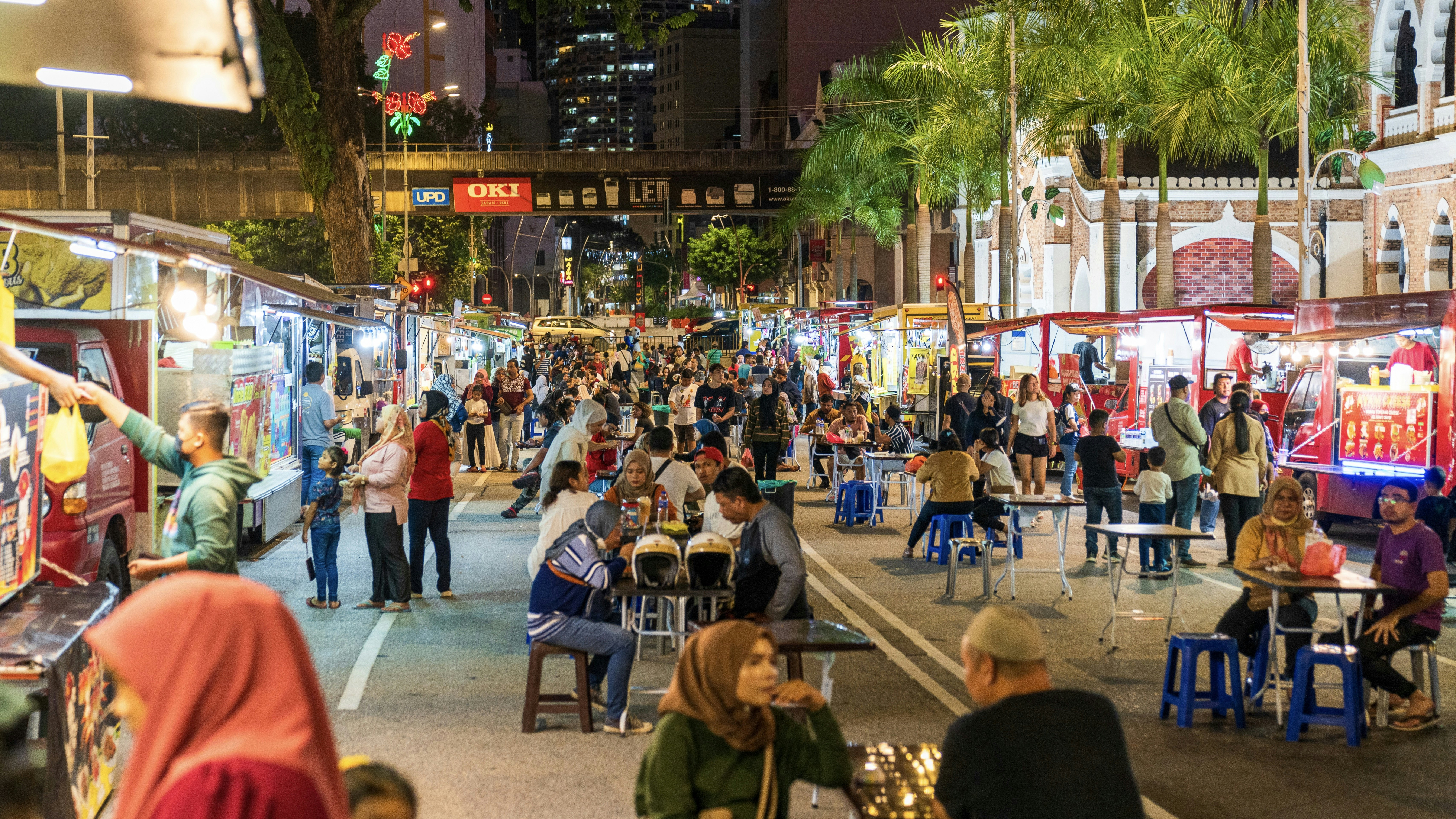 People sitting at tables in a street market
