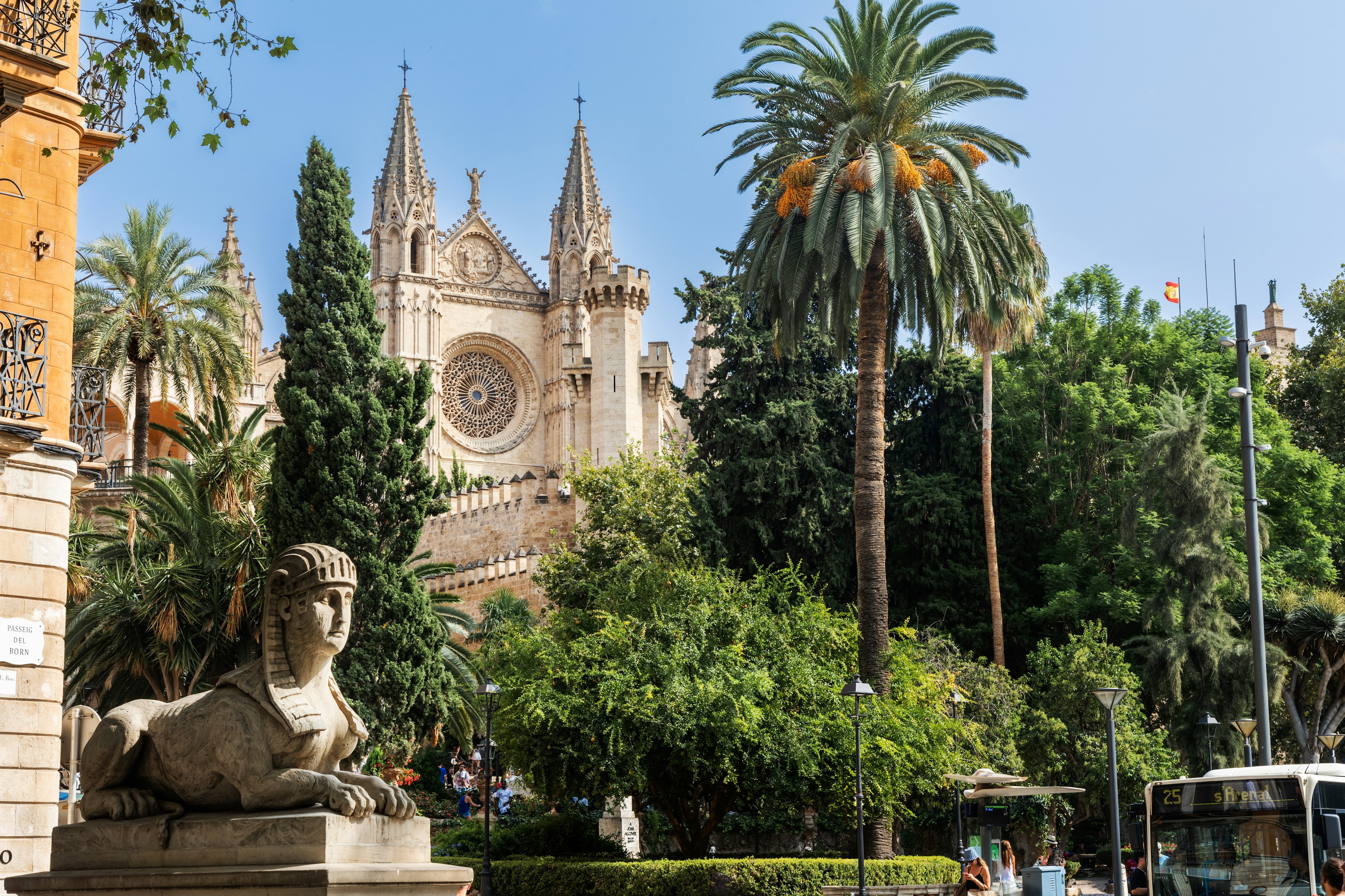 The Palma Cathedral framed by palm trees and a stone sphinx statue in Palma de Mallorca, Balearic Islands, Spain