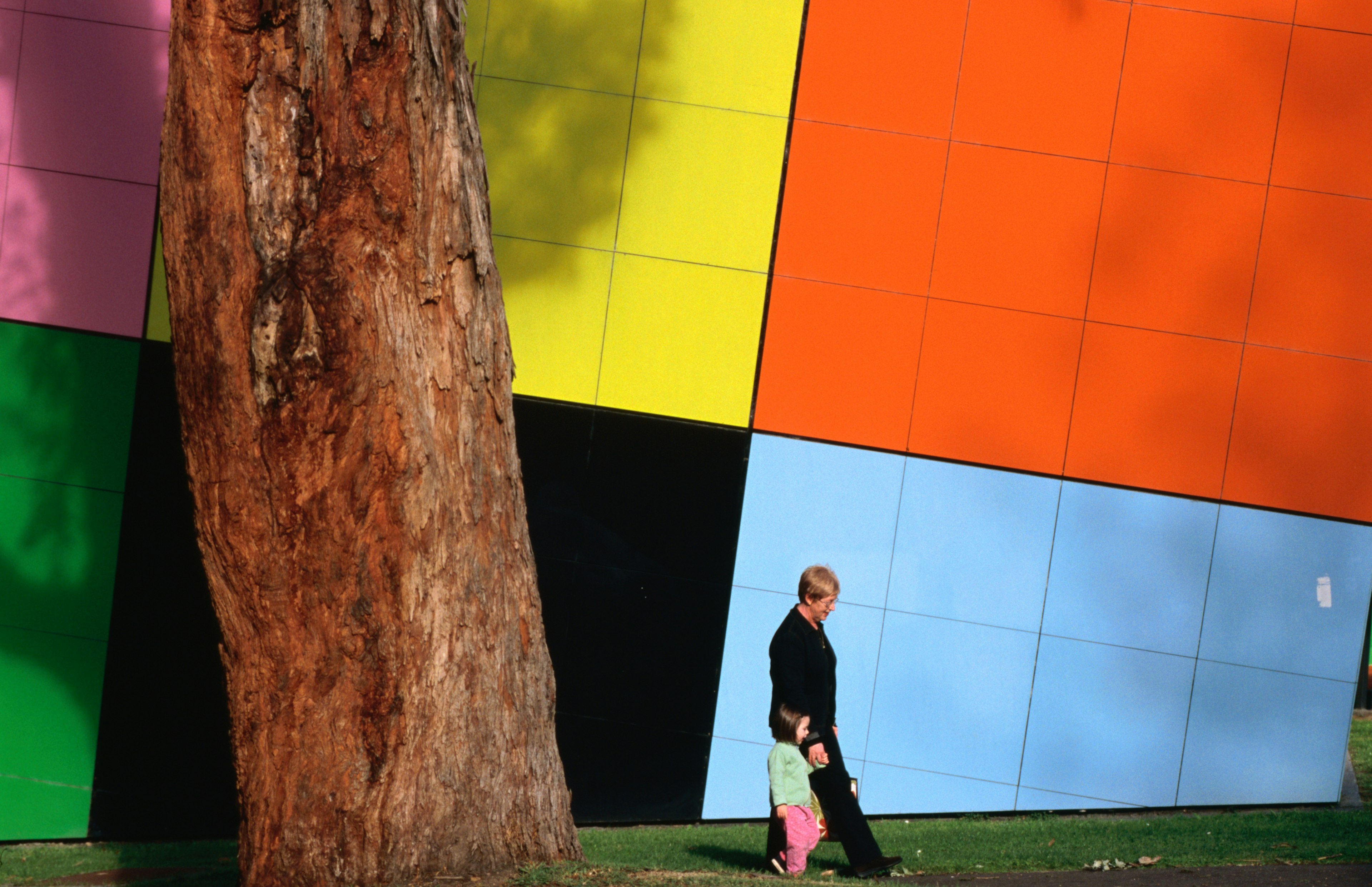 Melbourne Museum colorful facade with a woman and child walking past.