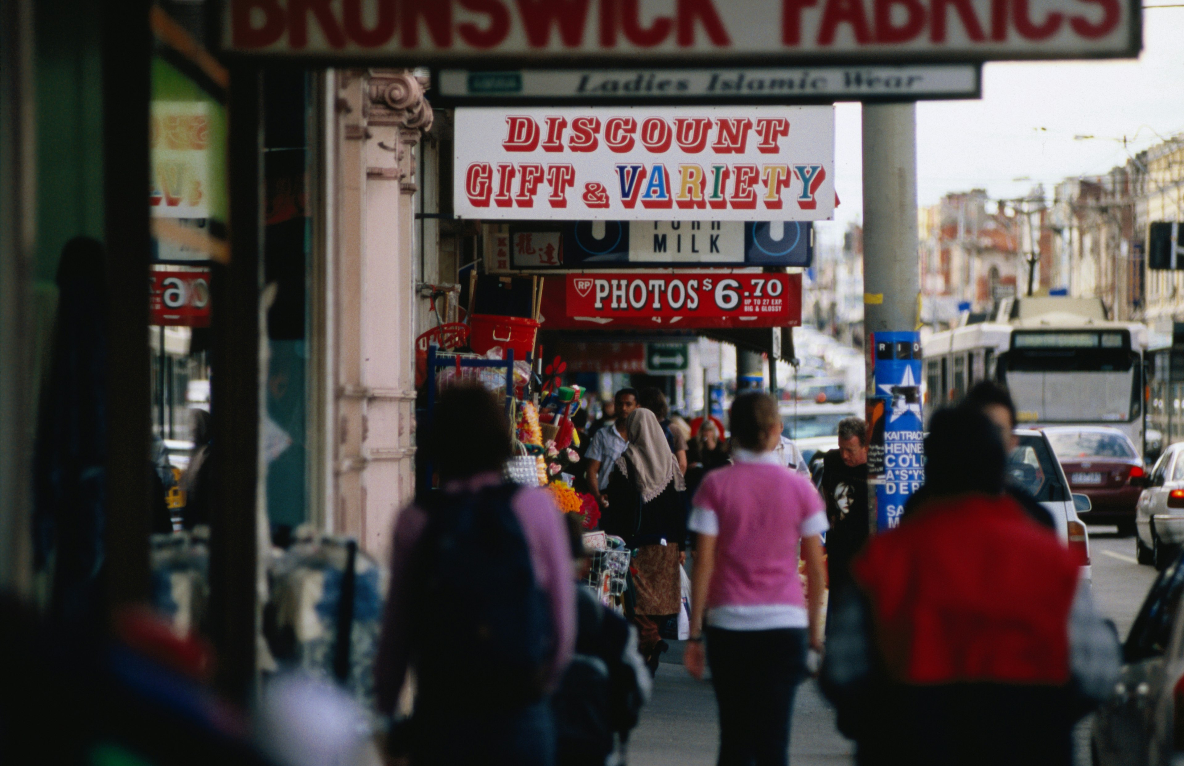 Sydney Road, Brunswick with shops fronts and pedestrians and a Melbourne tram in traffic